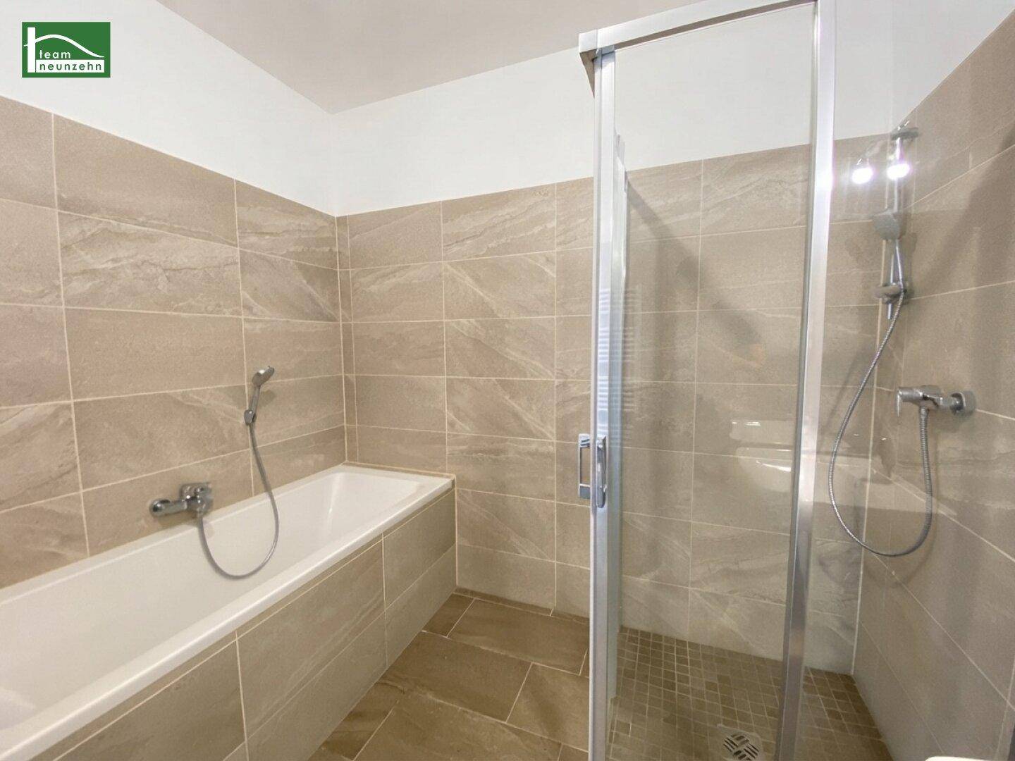 Modernes Badezimmer mit Badewanne, Duschkabine und beigefarbenen Fliesen.