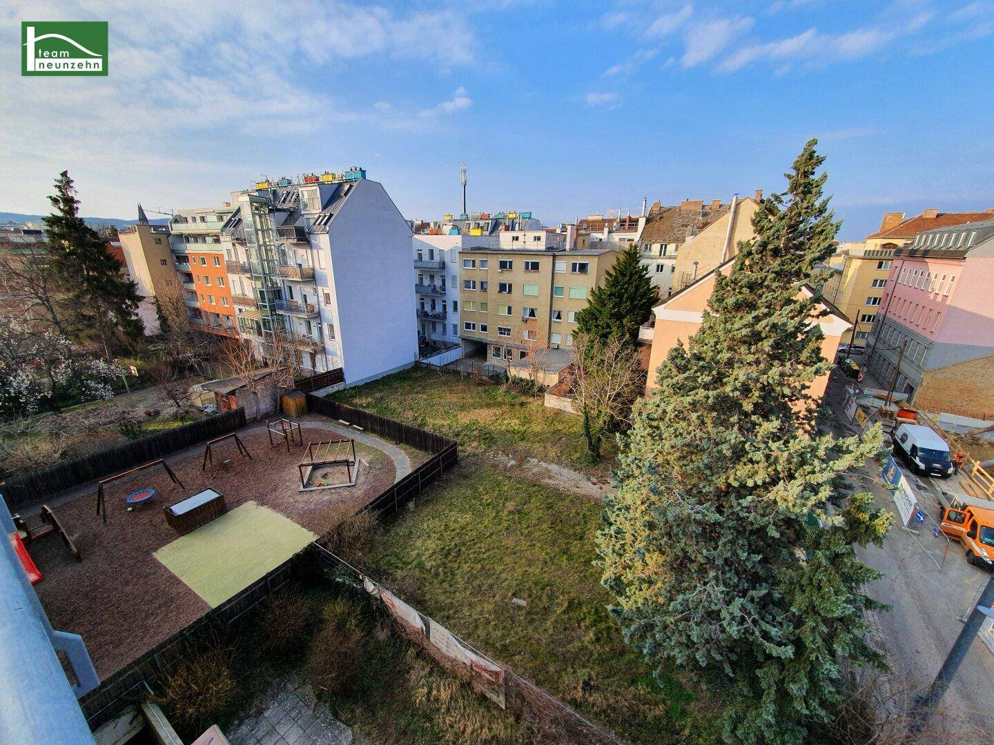 Blick von oben auf einen Spielplatz, umgeben von Wohngebäuden und einer Straße.