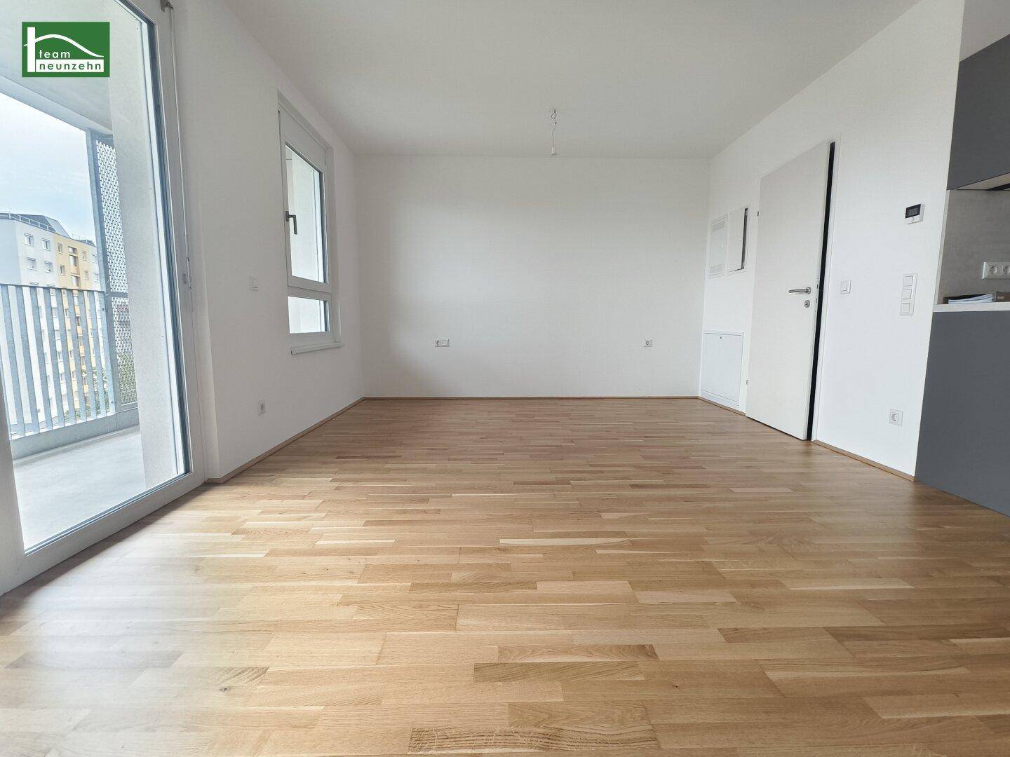 Heller Wohnbereich mit Zugang zum Balkon und Eichenparkettboden.