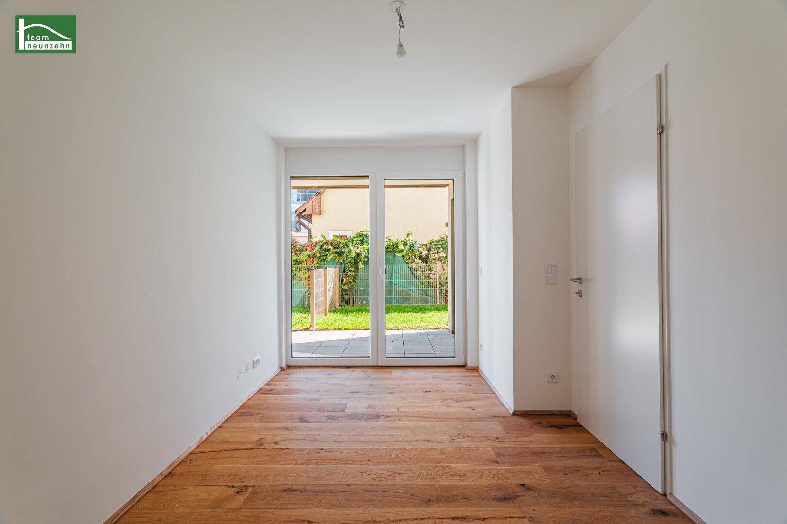 Heller Raum mit Holzboden und direktem Zugang zu einem kleinen Gartenbereich.