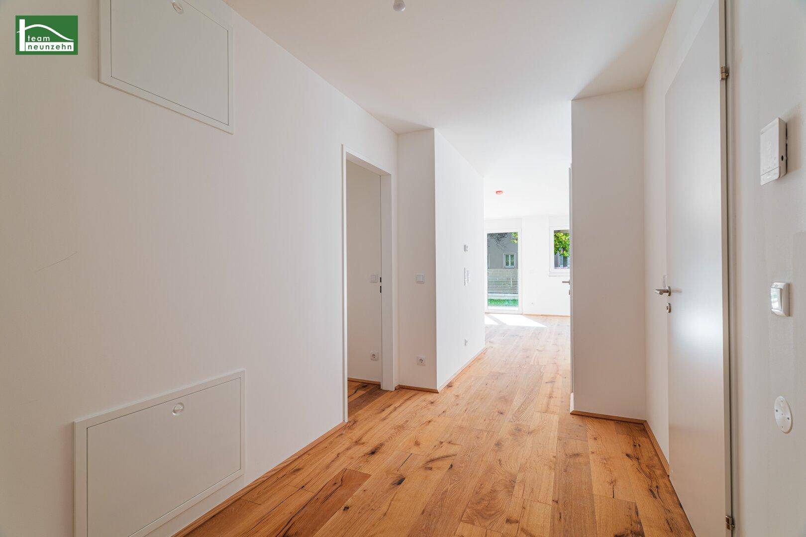 Heller Flur mit Holzboden und weißen Türen, der verschiedene Räume verbindet.