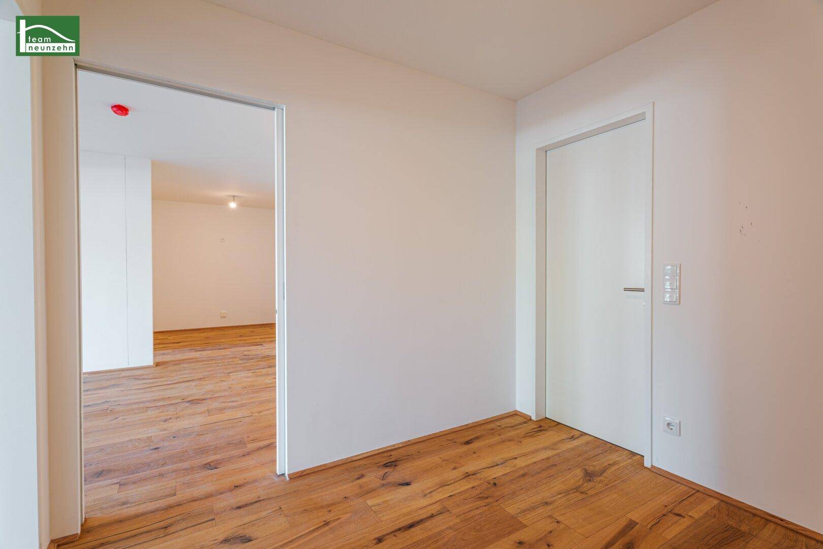 Heller Flur mit Holzboden und Zugang zu verschiedenen Räumen, modern und funktional gestaltet.