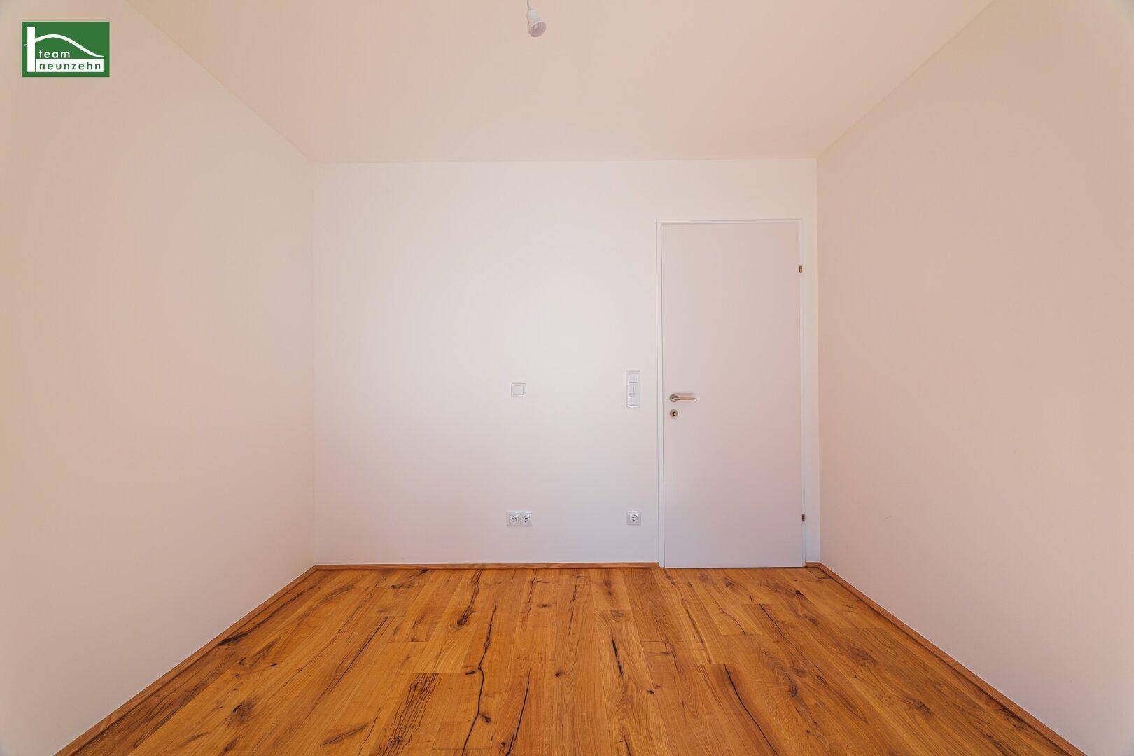 Unmöbliertes Zimmer mit Holzboden und weiß gestrichenen Wänden, bereit zur Einrichtung.