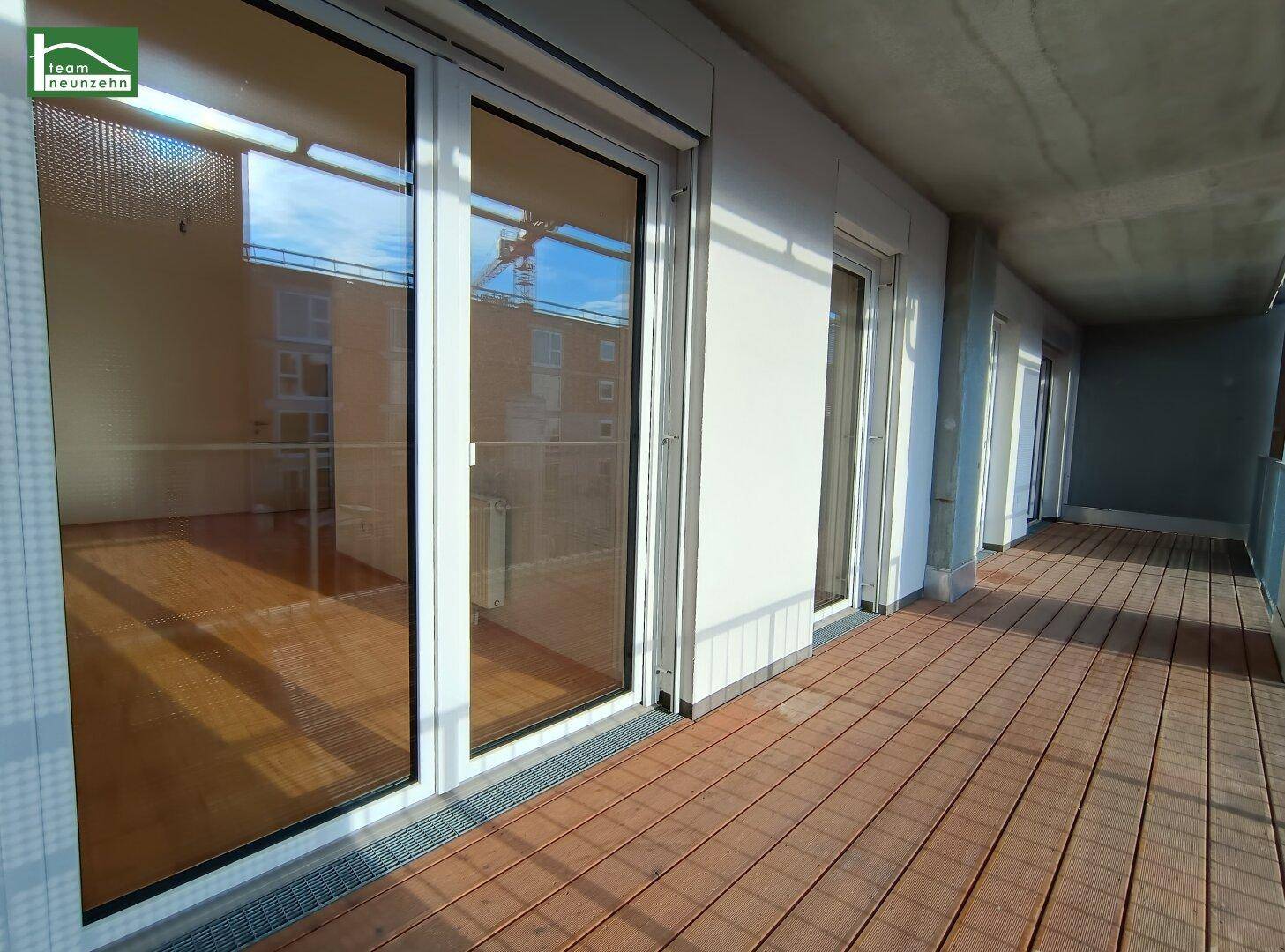 Geräumiger Balkon mit Holzboden und mehreren Zugängen zu den Innenräumen, ideal für Entspannung.