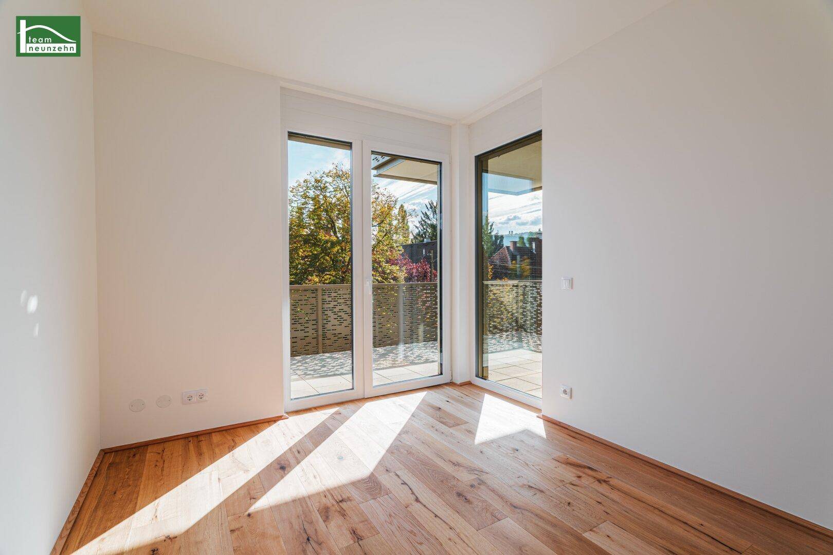Helles Zimmer mit Holzboden und Zugang zu einem Balkon, ideal für ein Schlafzimmer.