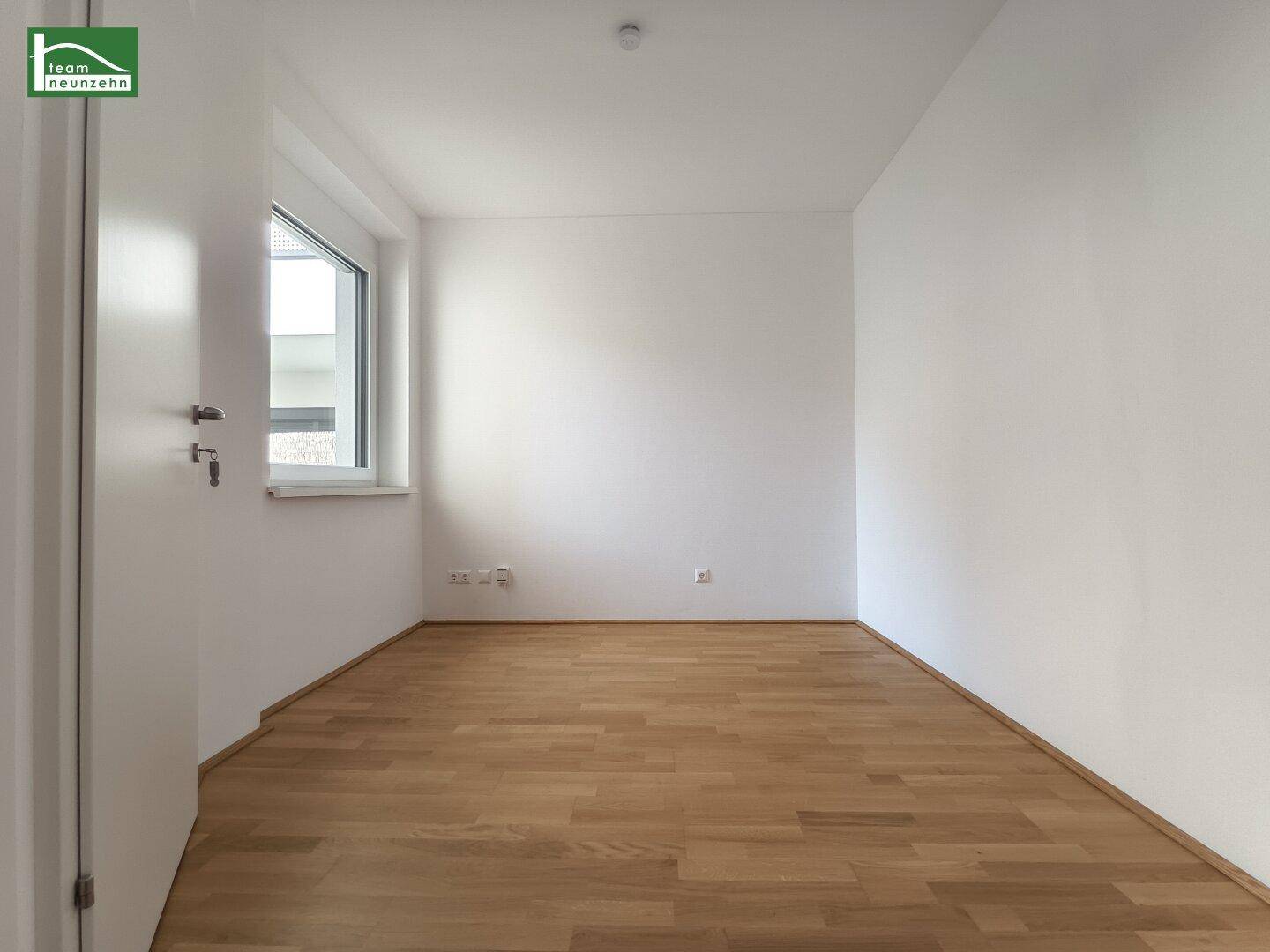 Helles, leeres Zimmer mit Parkettboden und einem Fenster, bereit zur individuellen Gestaltung.