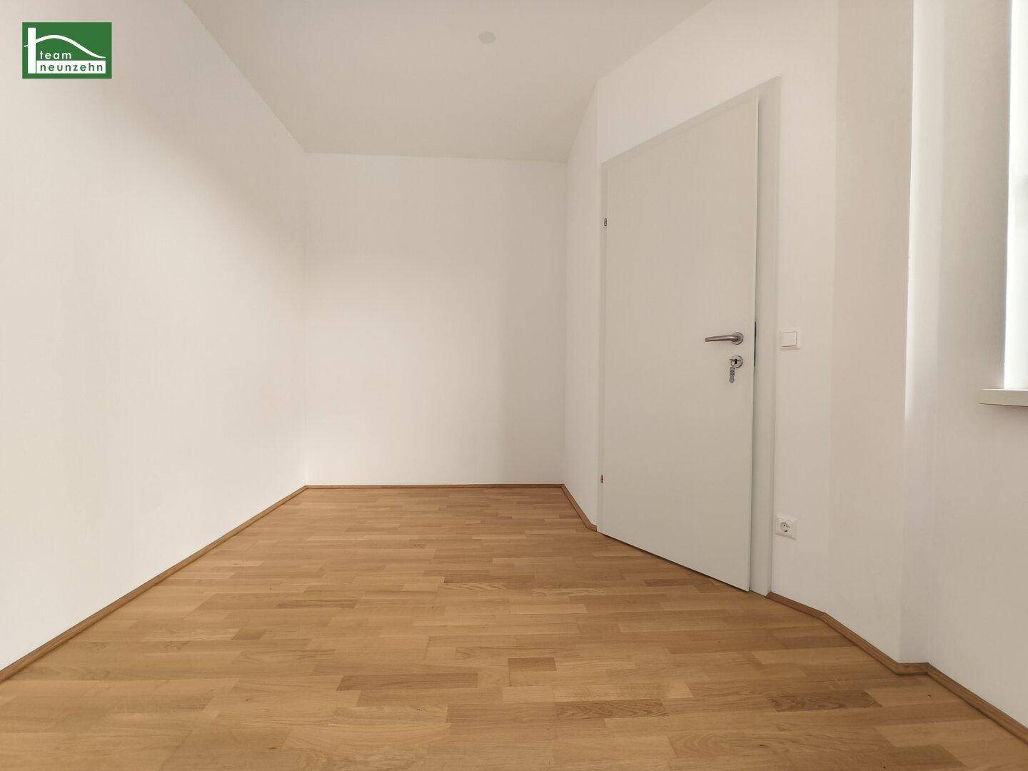 Leerer Raum mit Parkettboden und einer weißen Tür, bietet flexible Nutzungsmöglichkeiten.