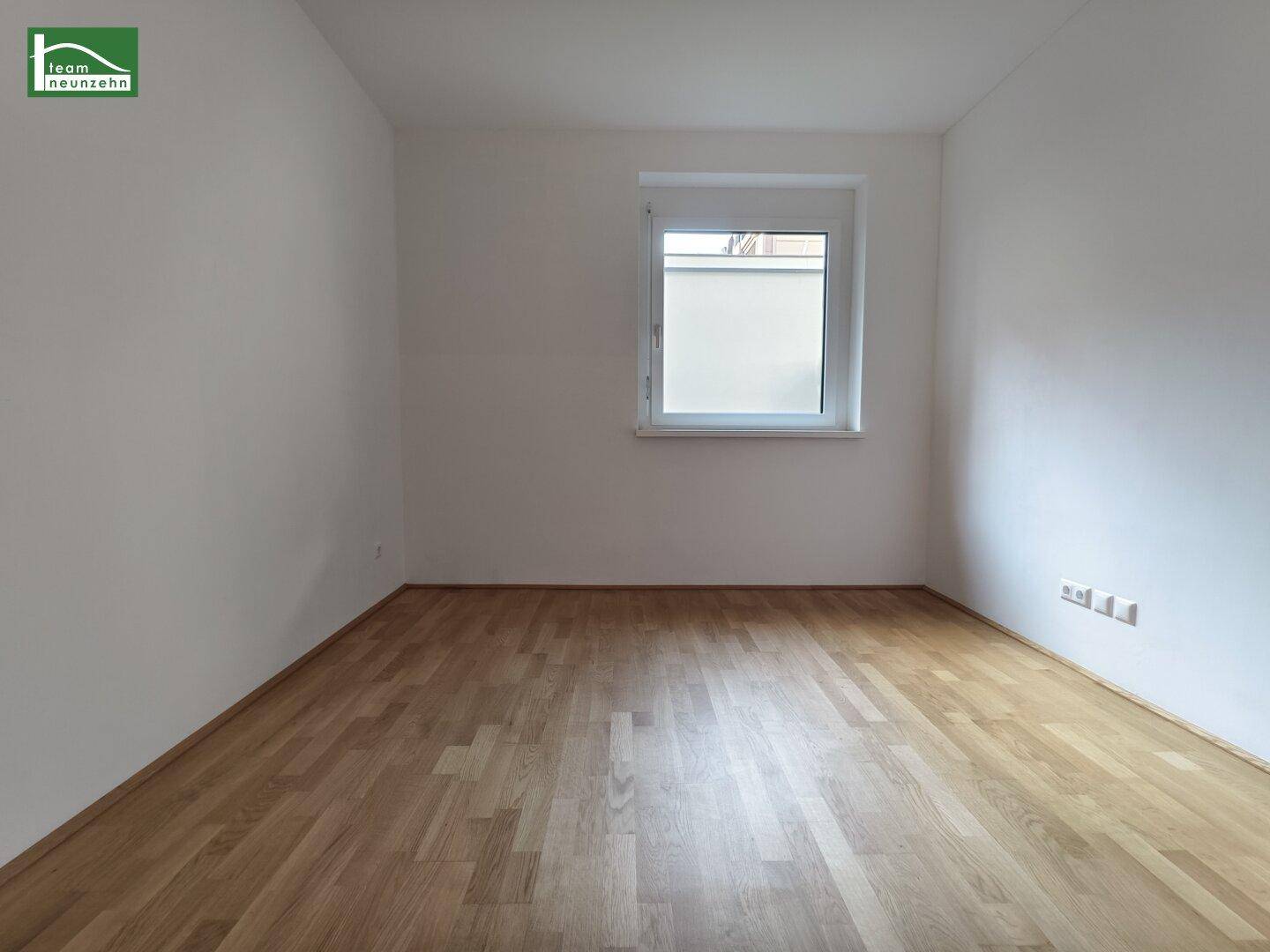 Helles, leeres Zimmer mit Parkettboden und einem Fenster, ideal als Schlaf- oder Arbeitszimmer.