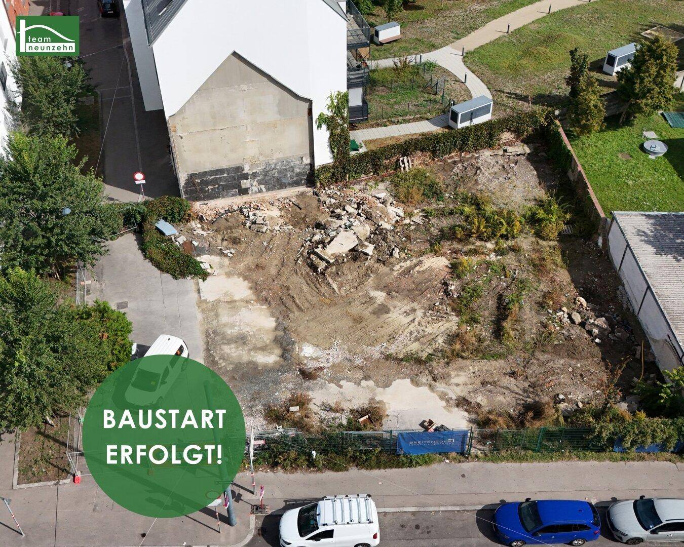 Luftaufnahme eines Baugrundstücks in städtischer Umgebung, umgeben von Bäumen und Hecken.