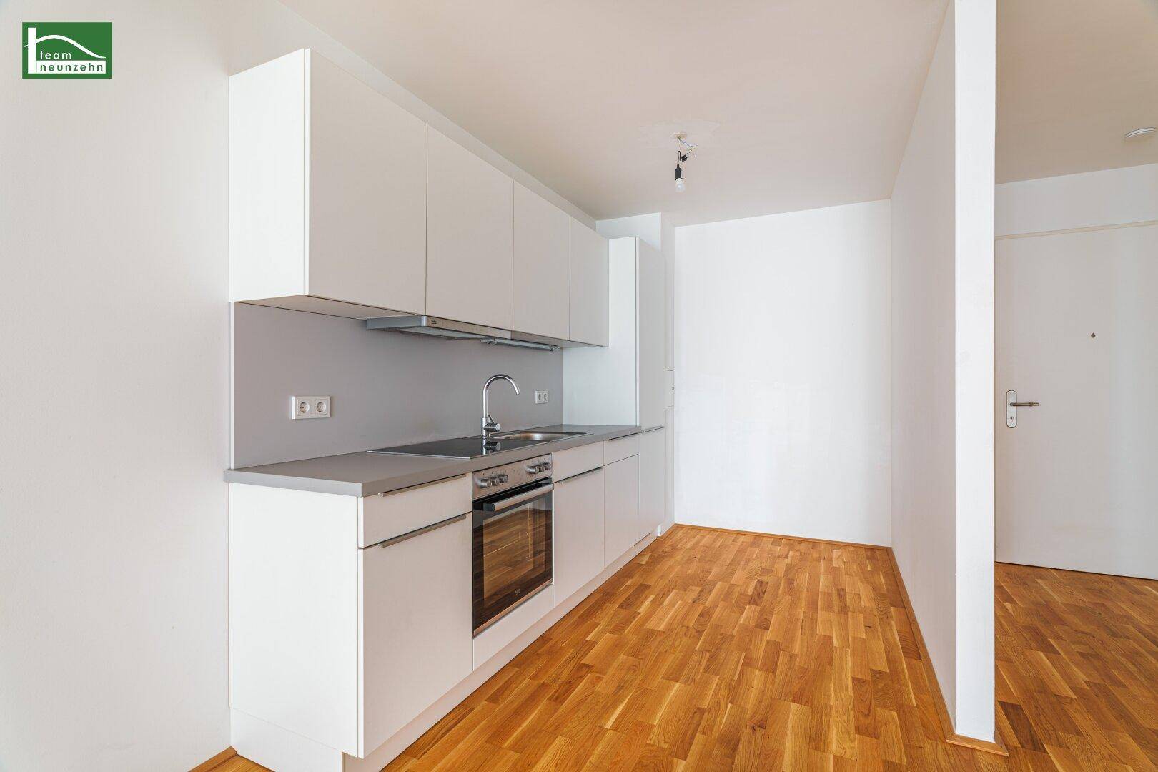 Moderne Küchenzeile in Weiß mit integriertem Backofen und viel Stauraum.