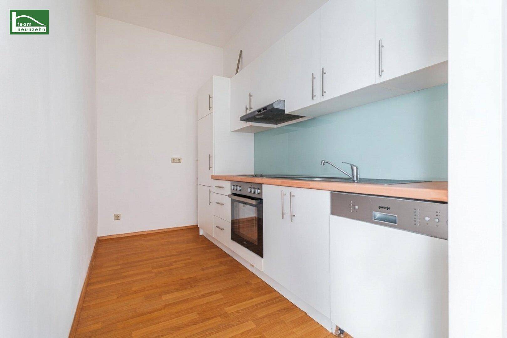 Funktionale Einbauküche mit weißen Schränken, Holztheke und integriertem Geschirrspüler.