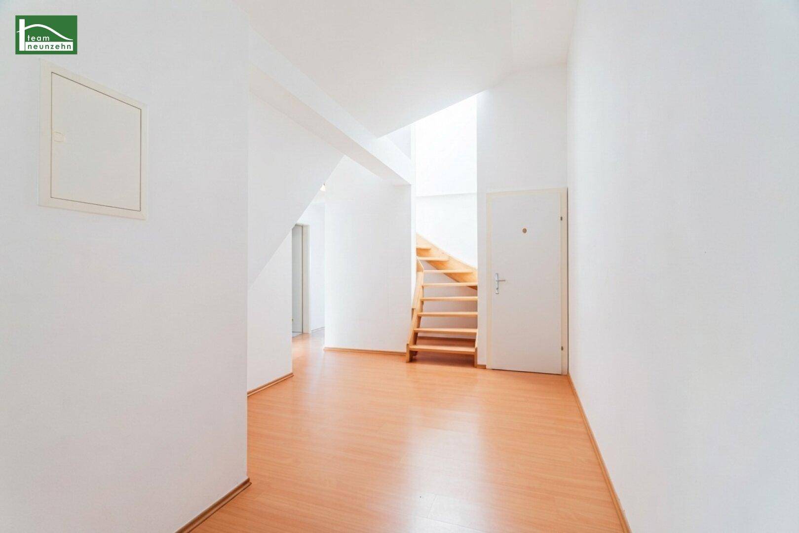 Geräumiger Flur mit Holztreppe, die in ein weiteres Stockwerk führt.