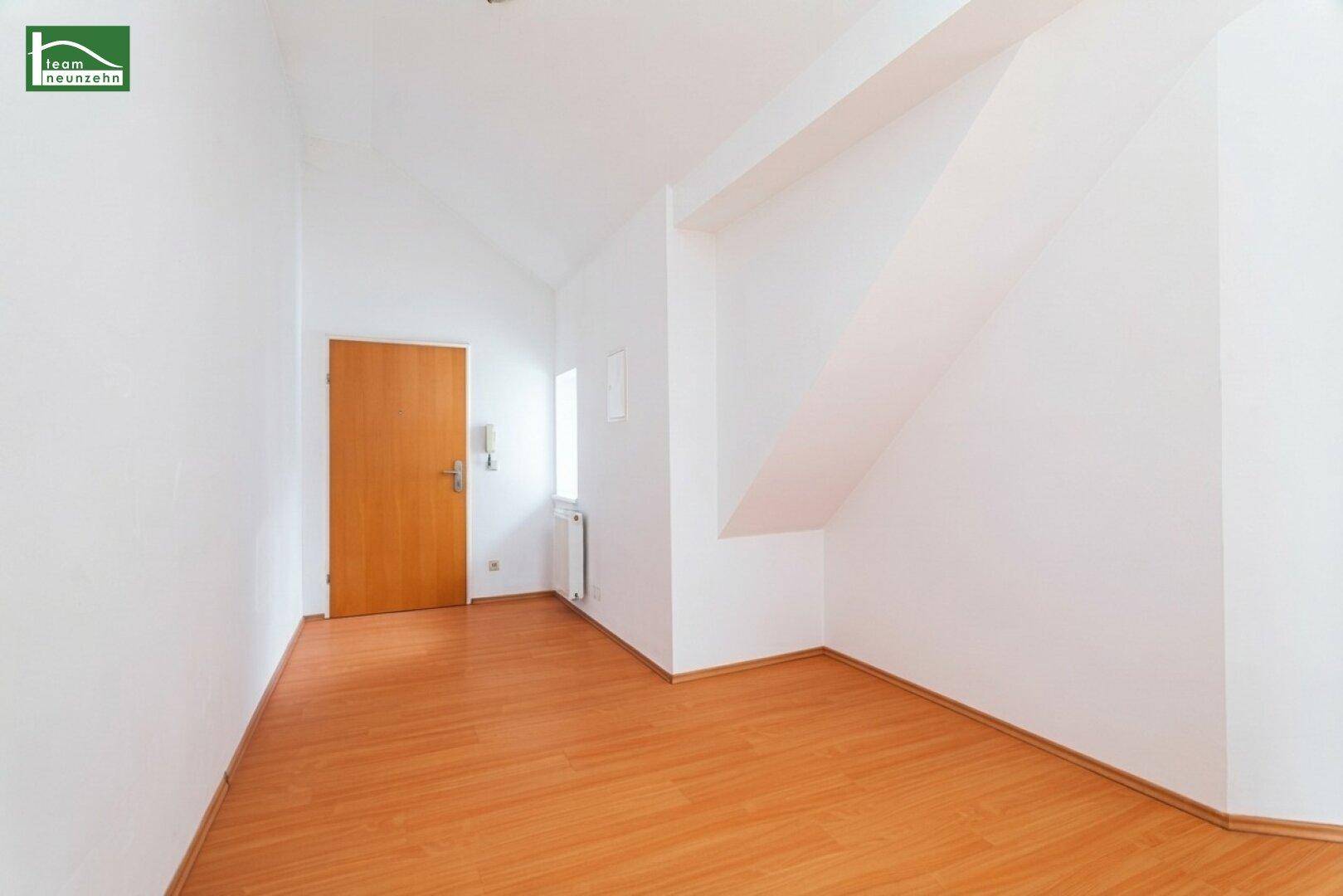 Eingangsbereich oder Flur mit Holzboden, weiß gestrichenen Wänden und einer Holztür.