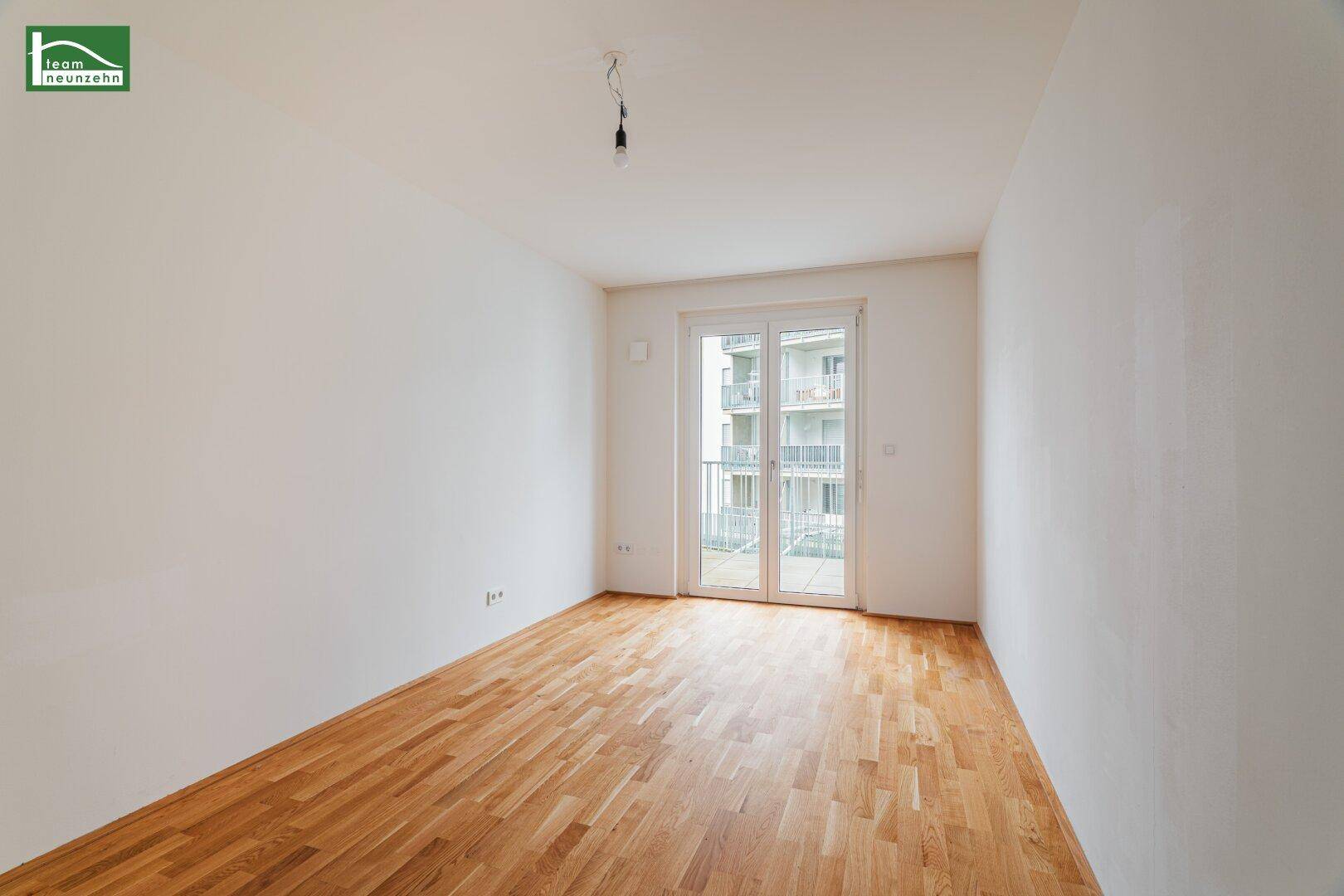 Helles Schlafzimmer mit Parkettboden und weißen Wänden, ausgestattet mit Zugang zu einem französischen Balkon.