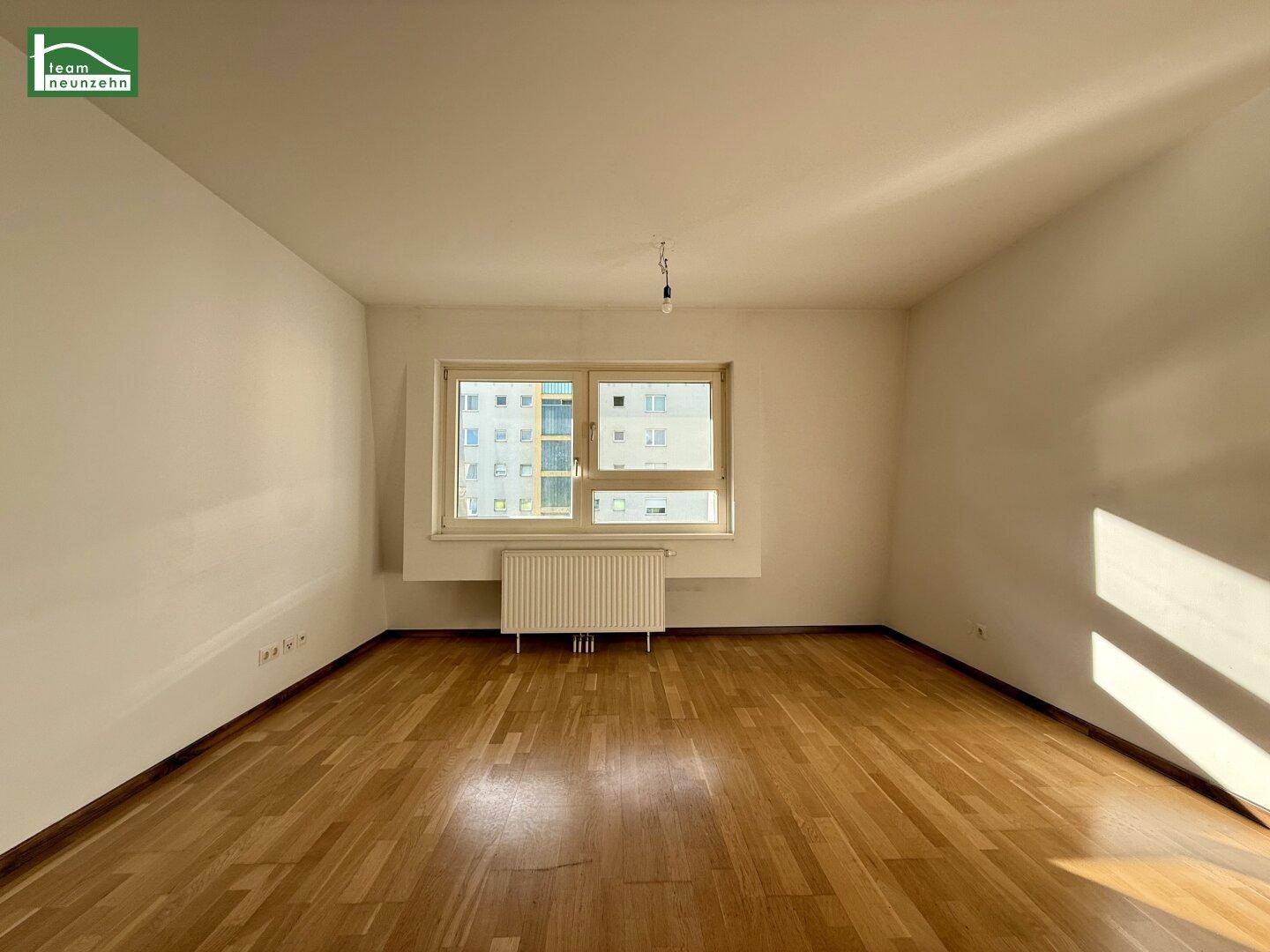 Leeres Zimmer mit Parkettboden und großem Fenster, bereit zur individuellen Gestaltung.