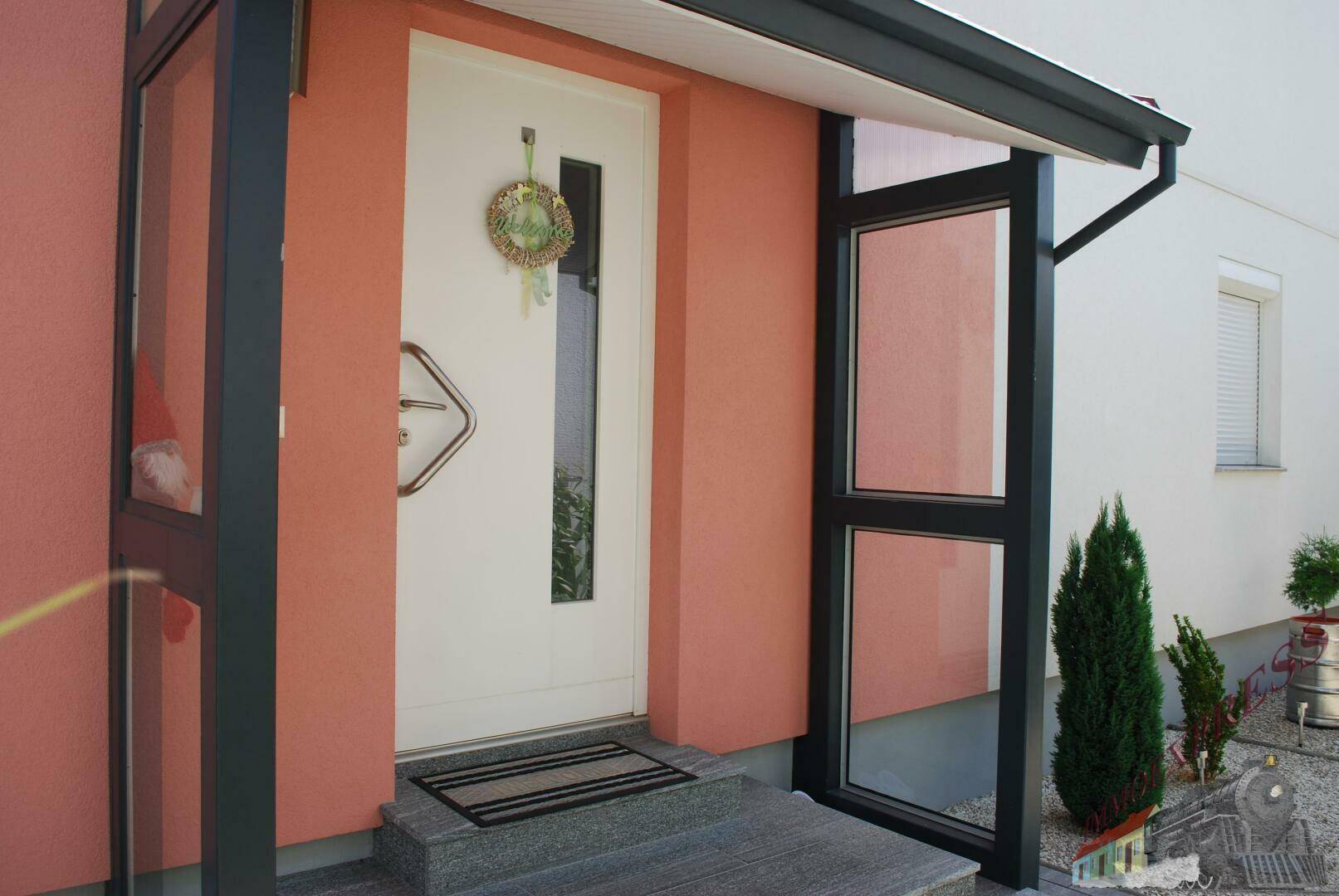 Haupteingang des Hauses mit moderner Tür und Vordach.
