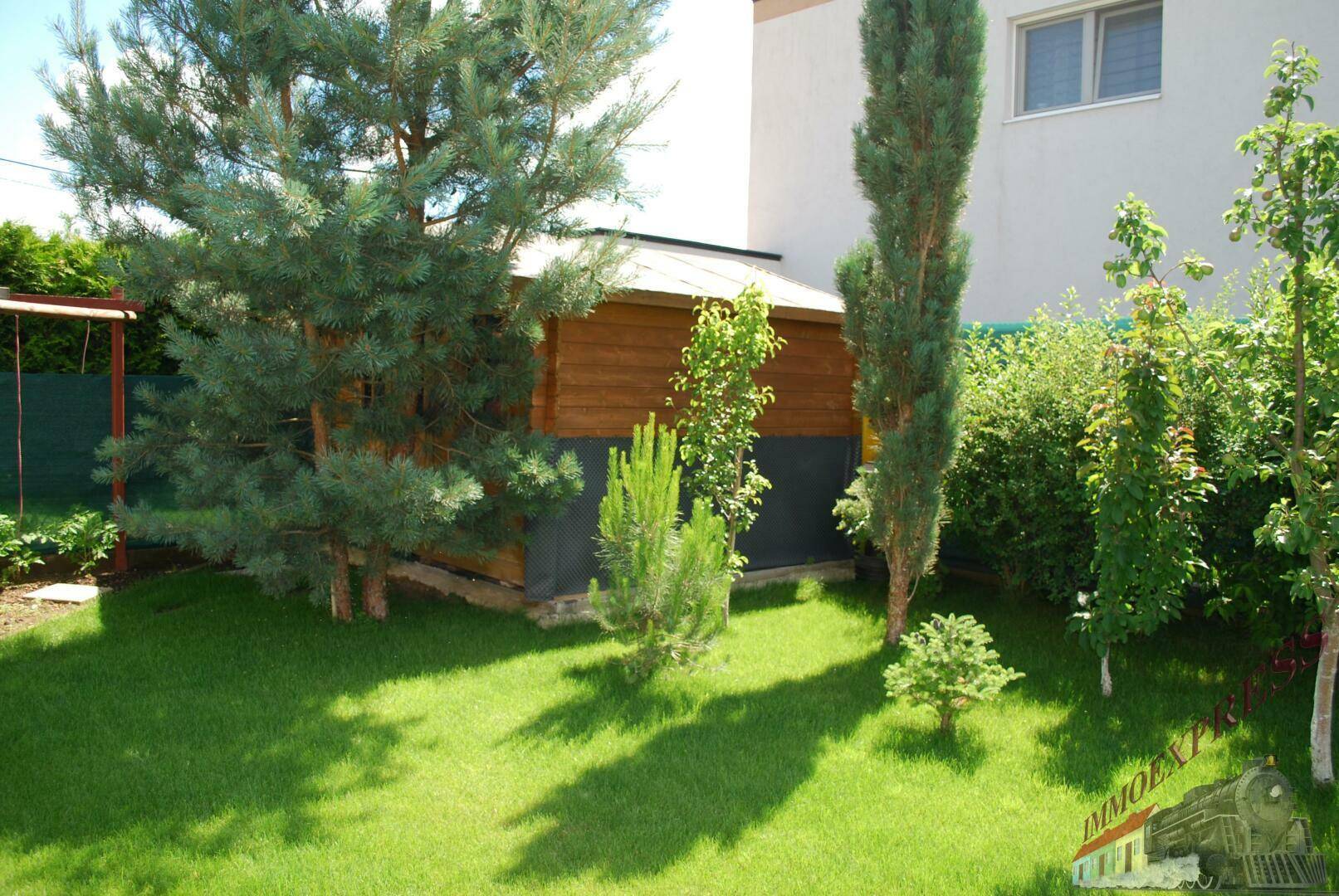 Gepflegter Garten mit Rasenfläche, verschiedenen Bäumen und einem Gartenhaus.