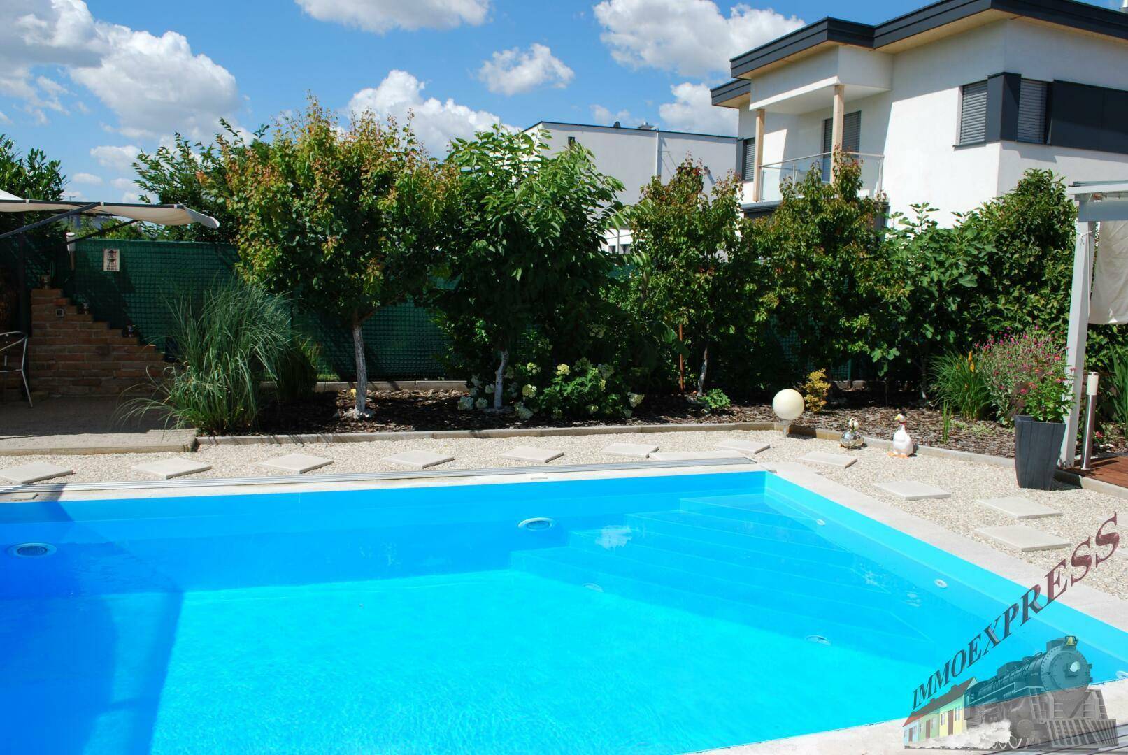Garten mit Swimmingpool, Kiesweg und verschiedenen Pflanzen.