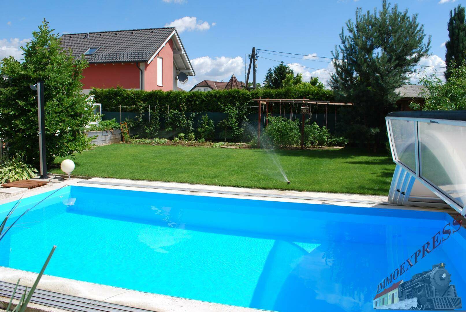 Sonniger Garten mit großem Swimmingpool, Rasenfläche und umliegender Bepflanzung.