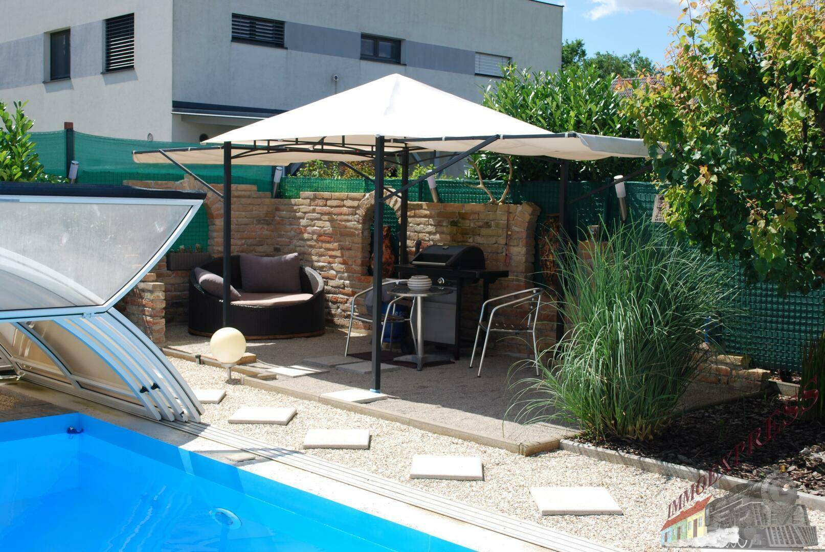 Gartenbereich mit Swimmingpool, Grillplatz und großem Sonnenschirm.