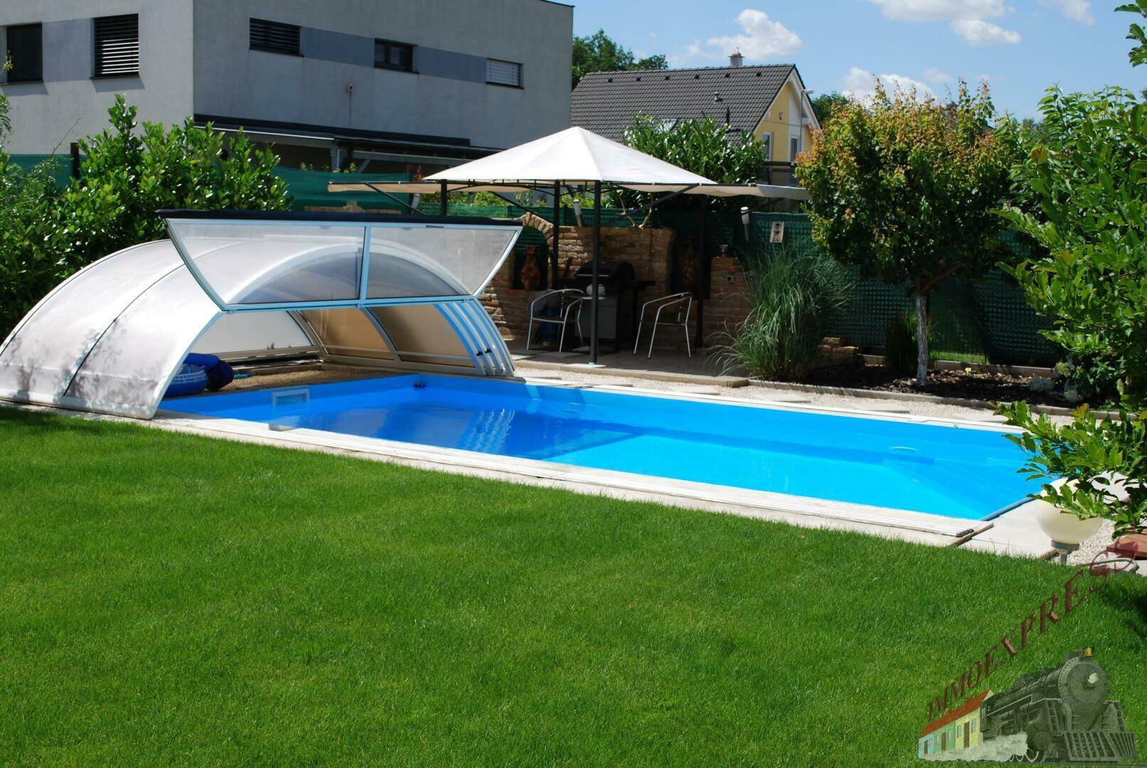 Sonniger Garten mit großem Swimmingpool, Rasenfläche und Schirm.