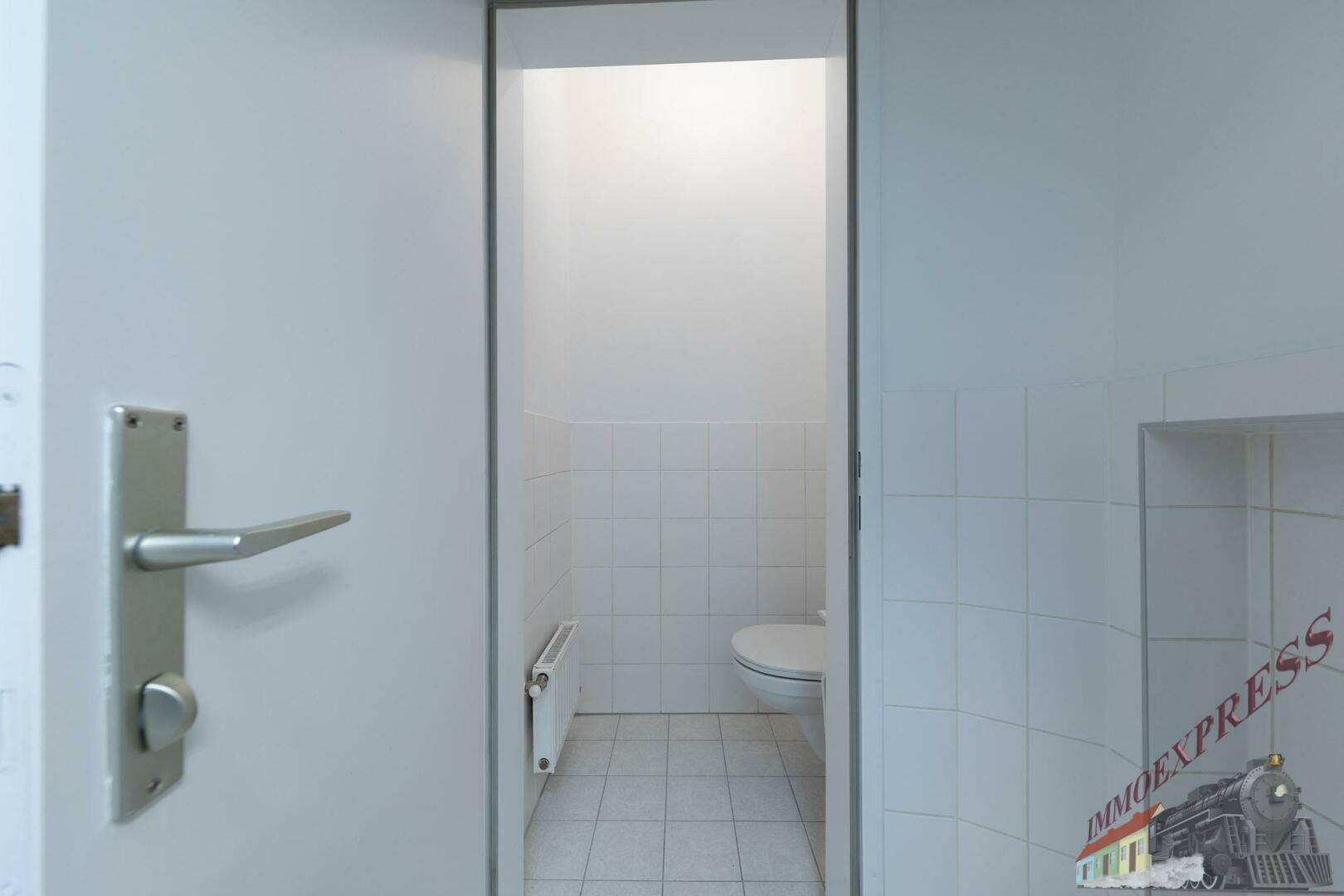 Kleines separates WC mit weiß gefliesten Wänden und Boden, funktional und sauber.