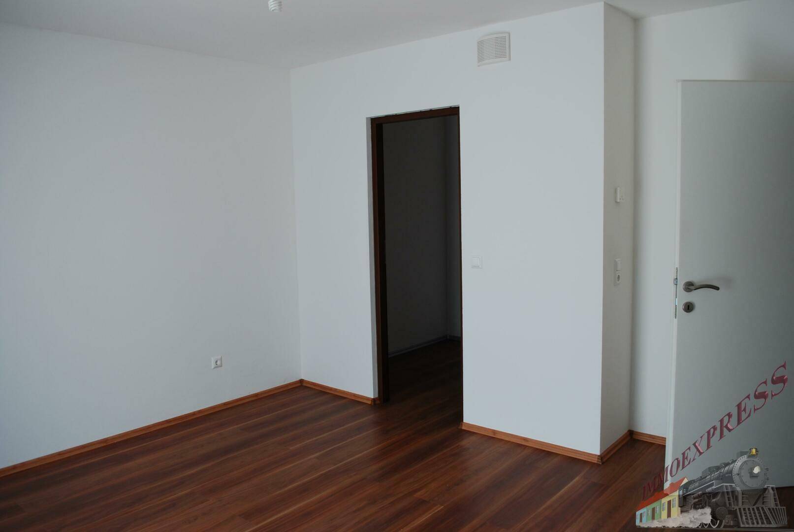Leeres Schlafzimmer mit Holzboden und weiß gestrichenen Wänden.