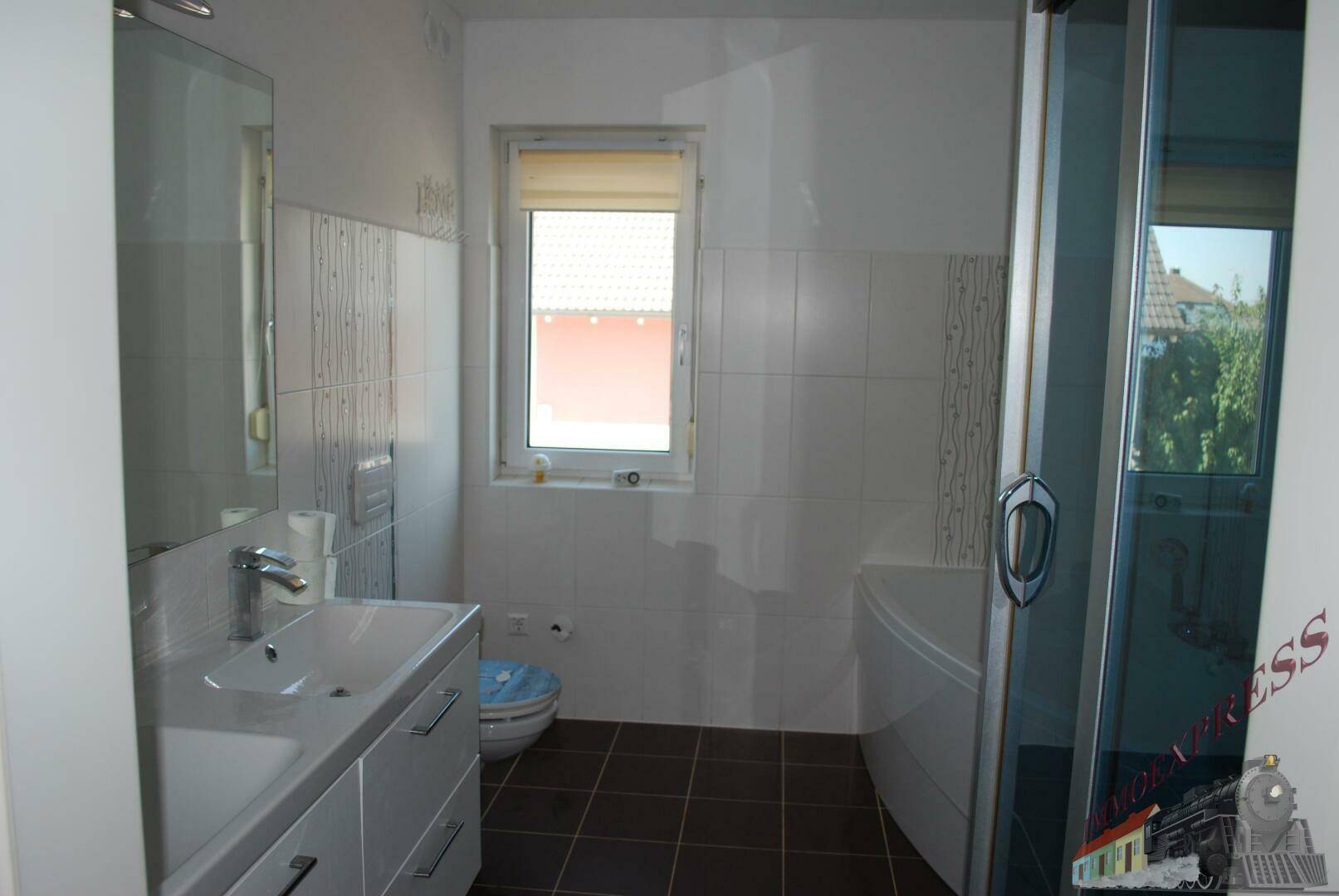 Modernes Badezimmer mit Waschbecken, Toilette, Dusche und Fenster.