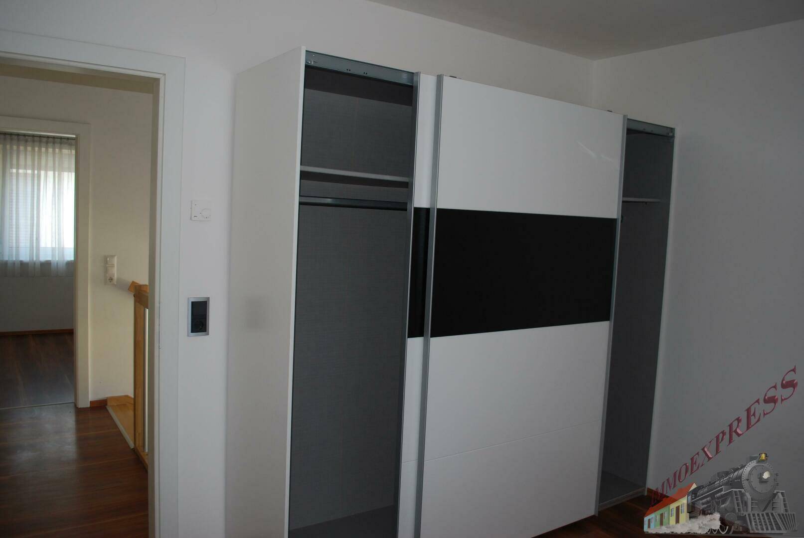 Flur mit modernem Schiebetürenschrank in Schwarz-Weiß-Optik.