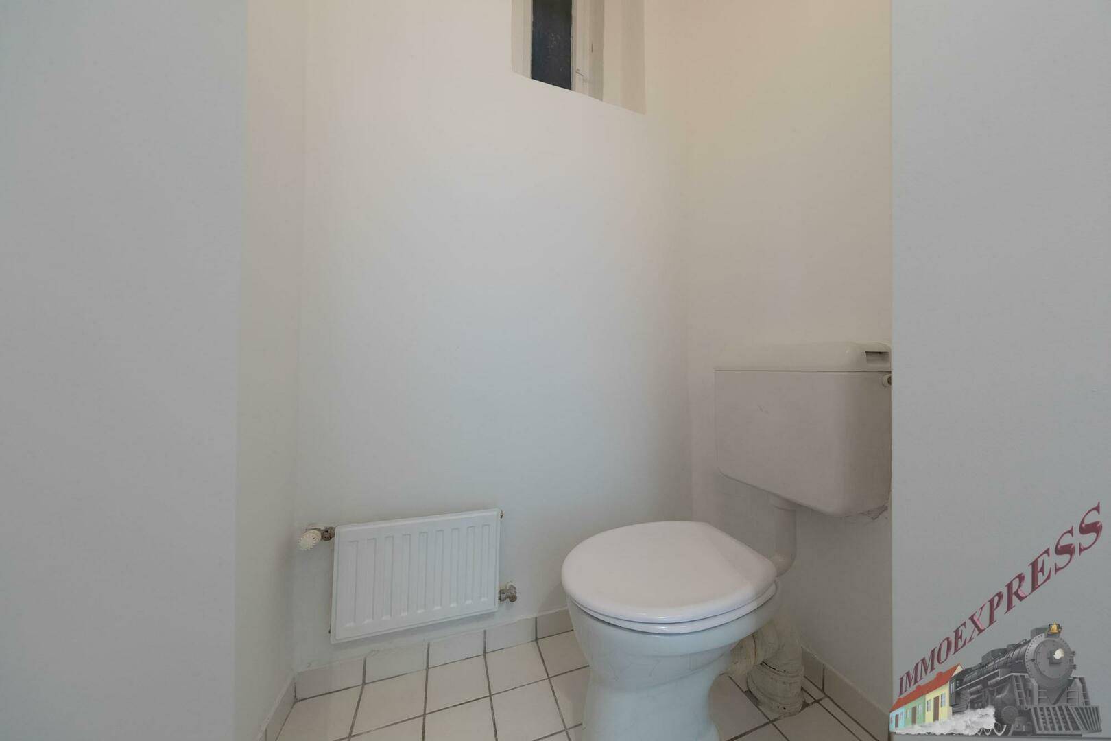 Kleines separates WC mit Toilette, Heizung und Fliesenboden.