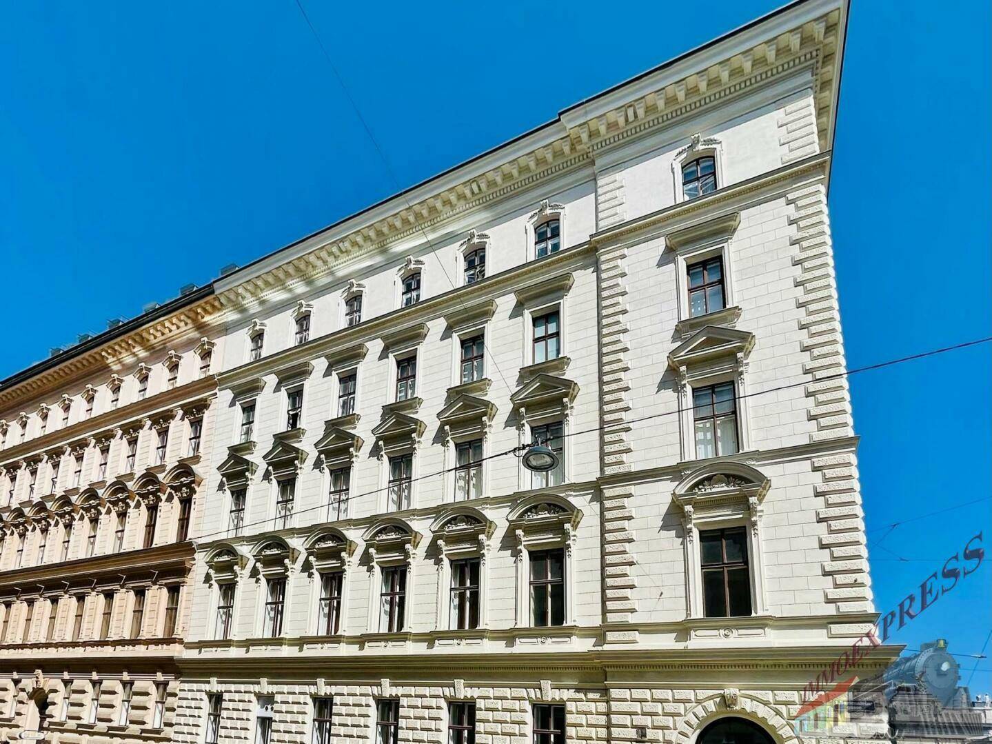Prächtiges historisches Gebäude mit reich verzierter Fassade und vielen Fenstern unter blauem Himmel.