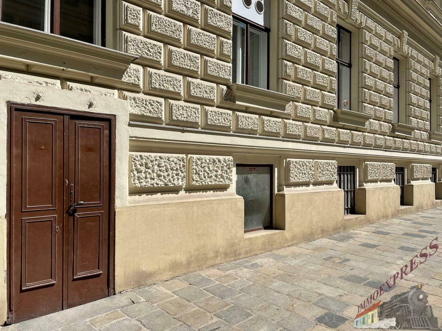 Detailansicht der historischen Fassade eines Gebäudes mit rustizierten Steinquadern und Holztüren.