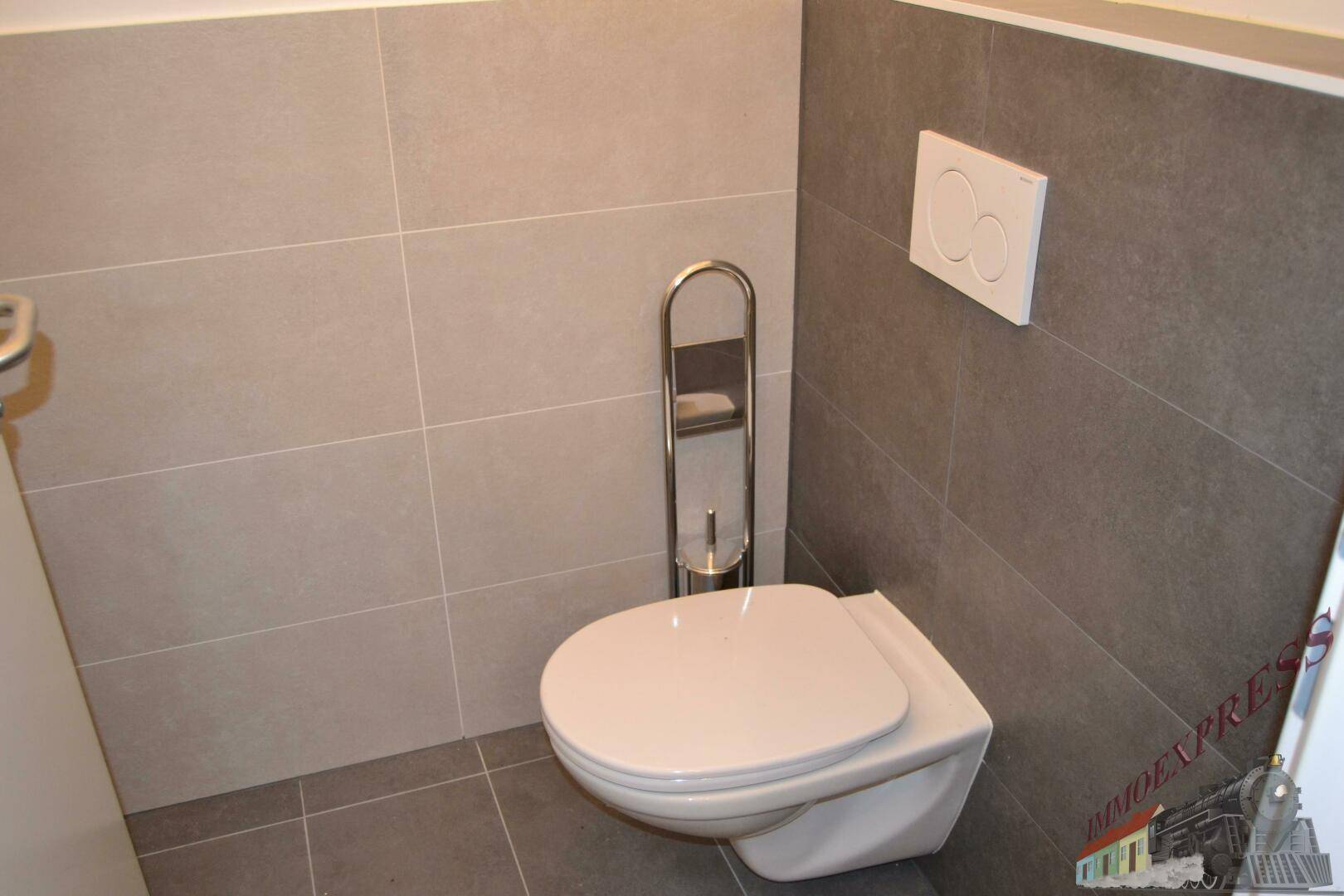 Modernes Wand-WC mit Spülkasten und Fliesen in zwei Grautönen, sehr gepflegt.