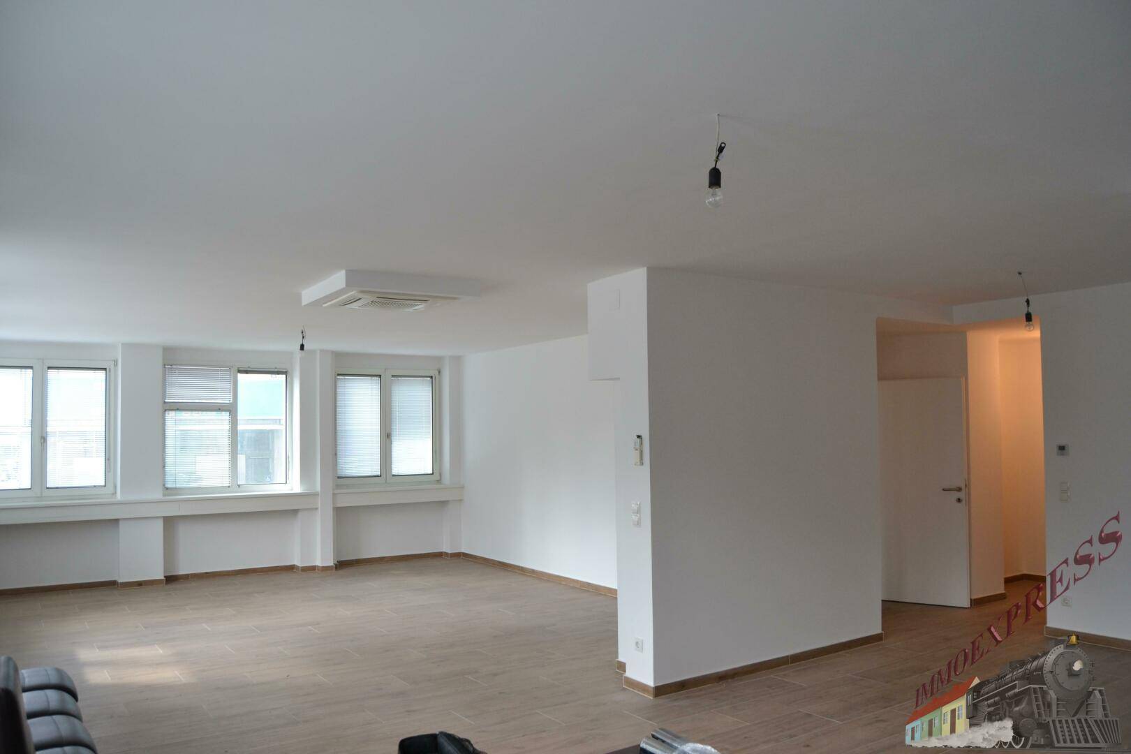 Heller Büroraum mit großen Fenstern und neutralen Wänden, ideal für flexible Gestaltung und Nutzung.