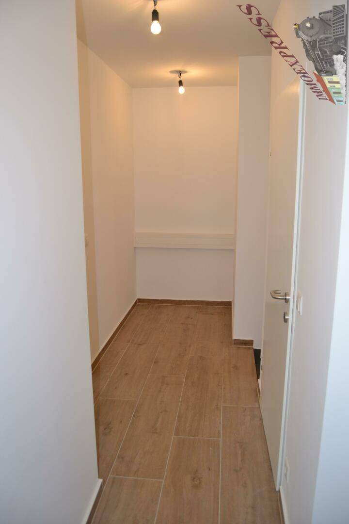 Heller Flur mit modernem Fliesenboden und weißen Wänden, führt zu weiteren Räumen im Gebäude.