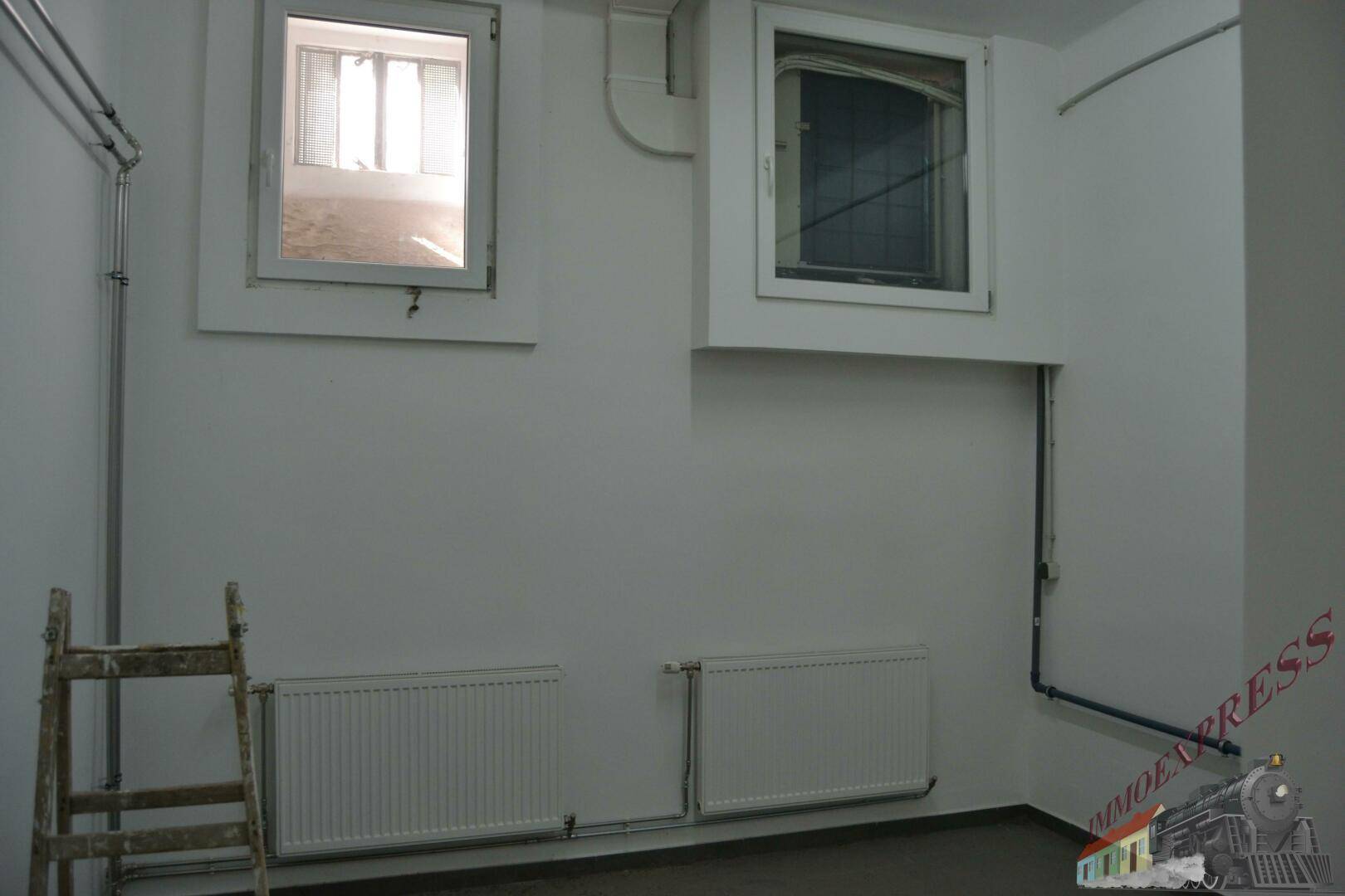Kellerraum mit zwei kleinen Fenstern und Heizkörpern, ideal als Lagerfläche nutzbar.