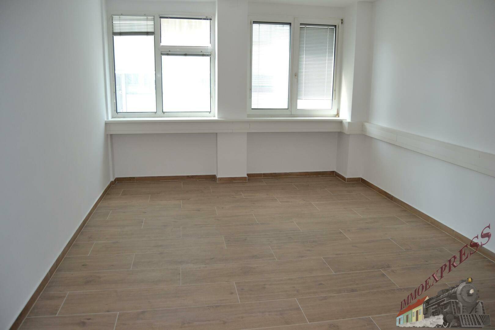 Heller Büroraum mit zwei großen Fenstern und modernem Fliesenboden, bietet viel Tageslicht.