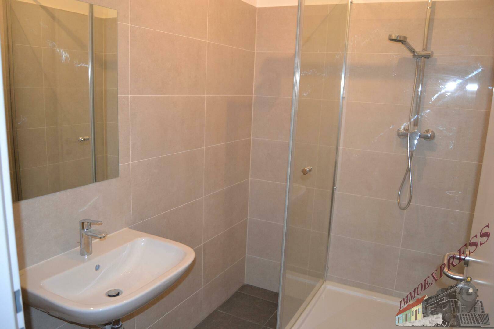 Helles Badezimmer mit Duschkabine, Waschbecken und modernen Fliesen, in gutem Zustand.