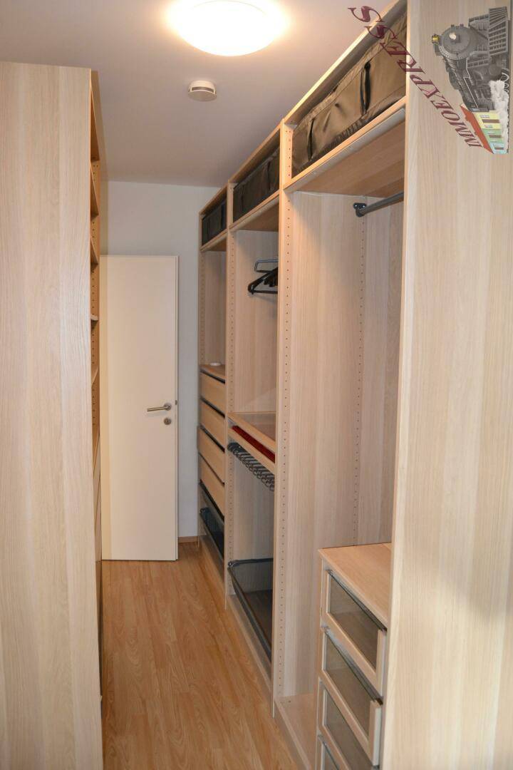 Geräumiger begehbarer Kleiderschrank mit offenen Regalen und Schubladen für viel Stauraum.