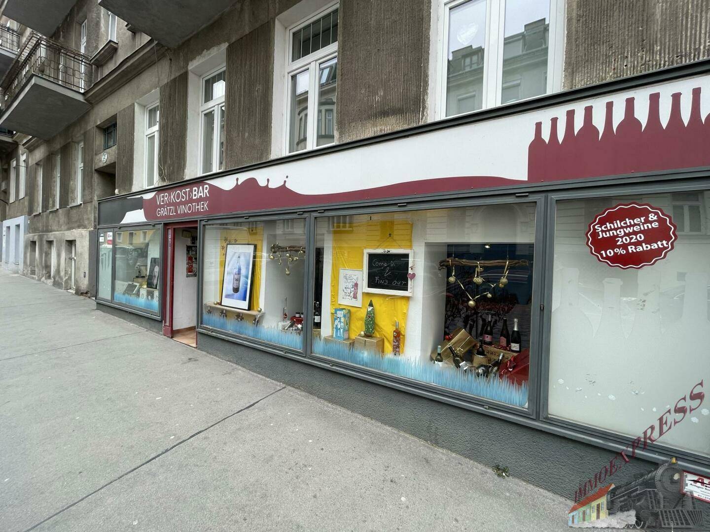 Fassade eines Geschäftsgebäudes mit großen Schaufenstern und Werbeaufschriften an der Straße.