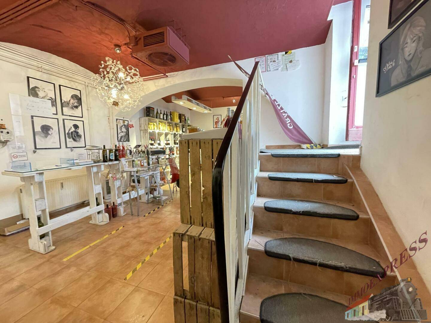 Blick auf eine Treppe in einem Verkaufsraum mit Fliesenboden und dekorativer Deckenbeleuchtung.