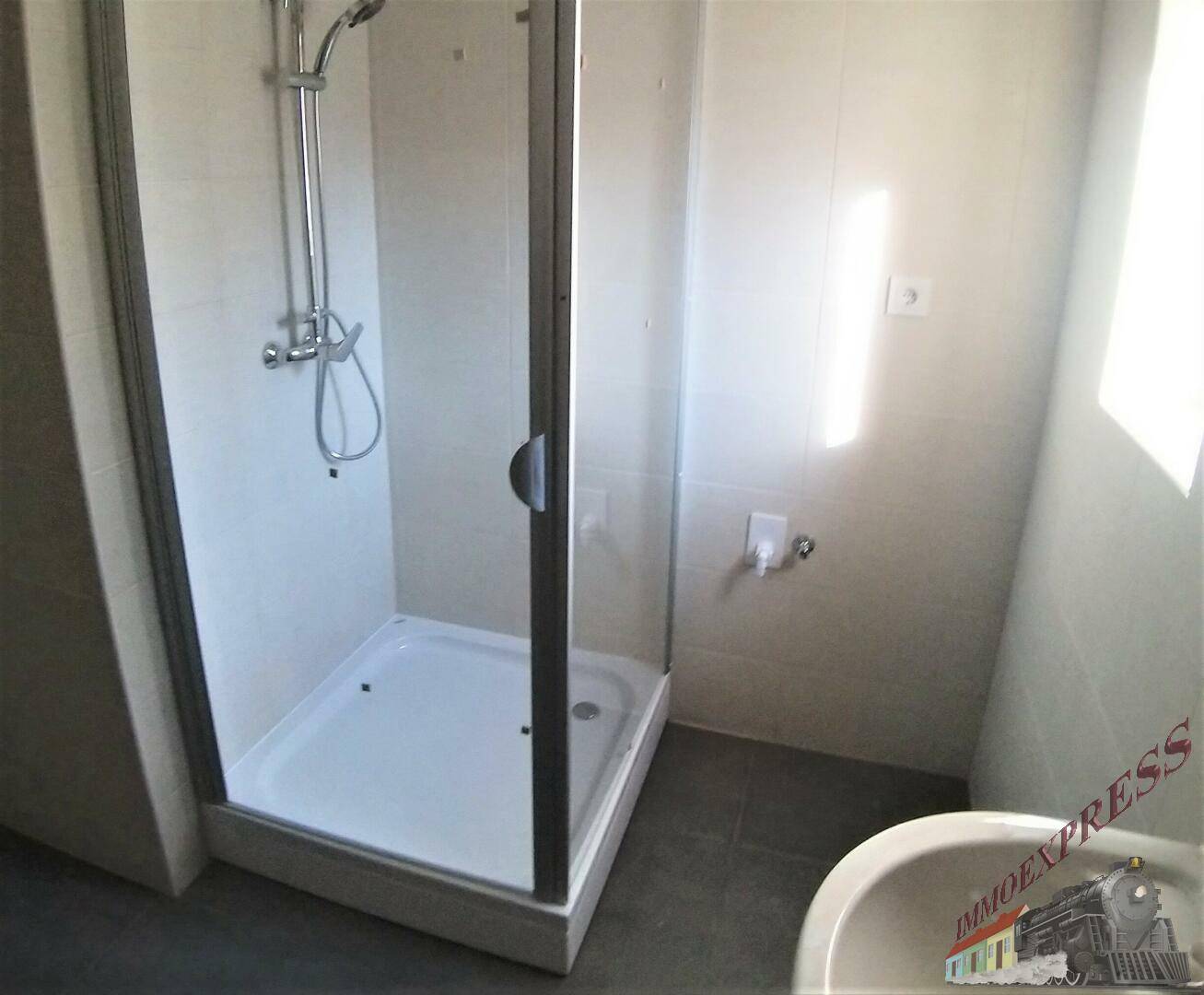 Badezimmer mit moderner Glasduschkabine und hellen Fliesen an Wänden und Boden.