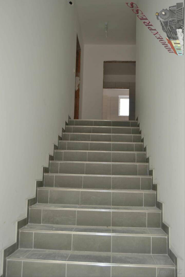 Geräumige Treppe mit grauen Fliesen führt in die oberen Stockwerke des Gebäudes.