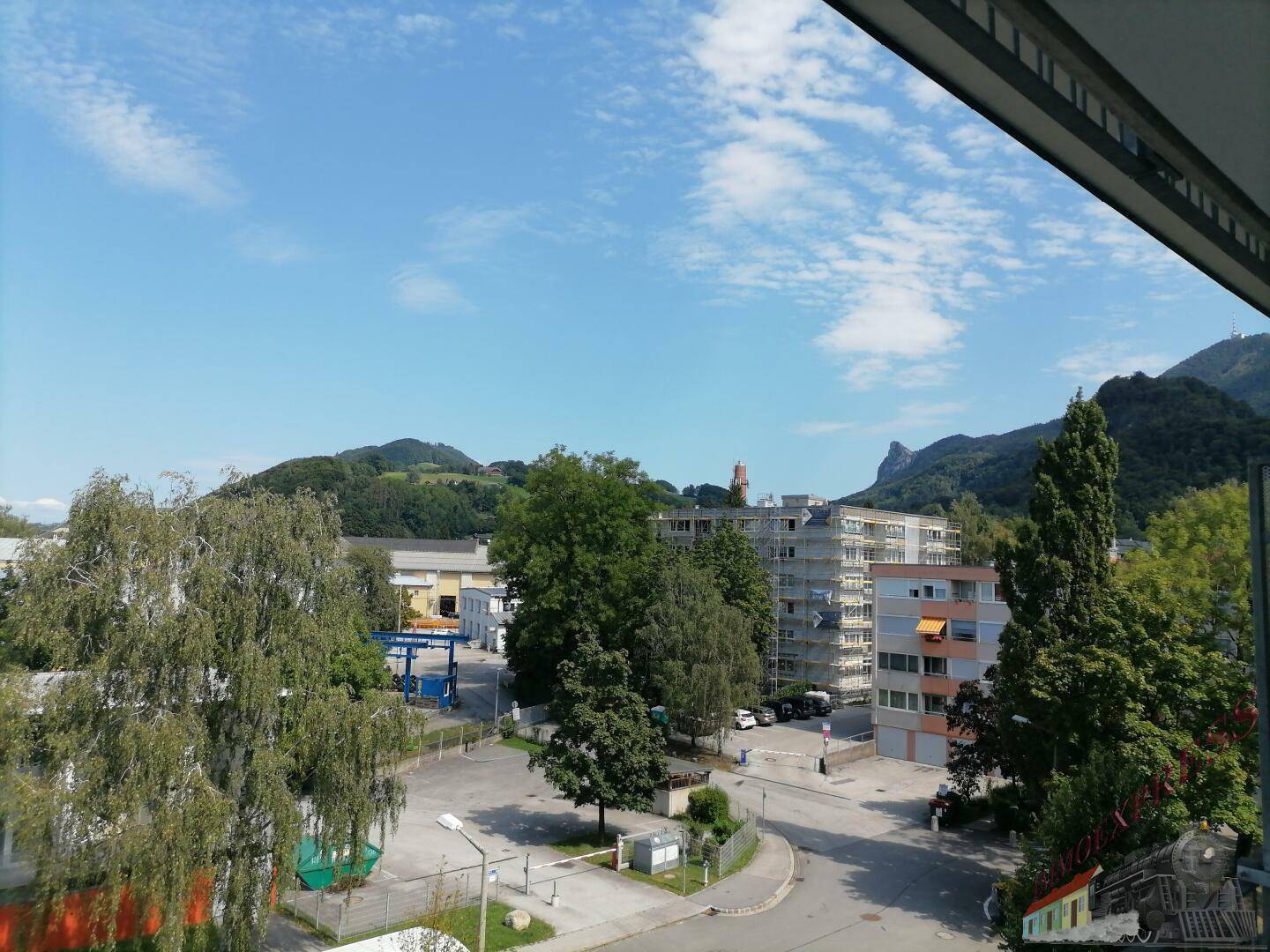 Weitläufiger Blick auf die Umgebung mit Bergen, Bäumen und anderen Gebäuden.