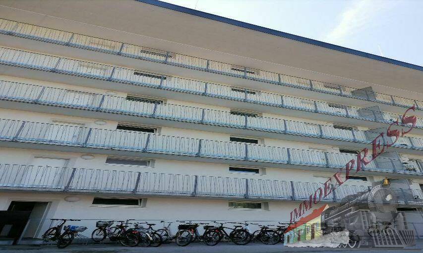 Fassade eines Mehrfamilienhauses mit zahlreichen Balkonen und Fahrradabstellplätzen.