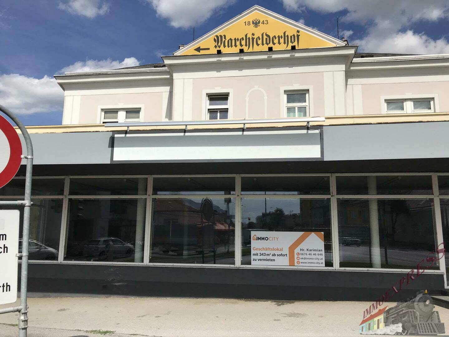 Geschäftsfassade mit großen Schaufenstern und einem Vermietungsschild, das die verfügbare Fläche anzeigt, an einem sonnigen Tag.