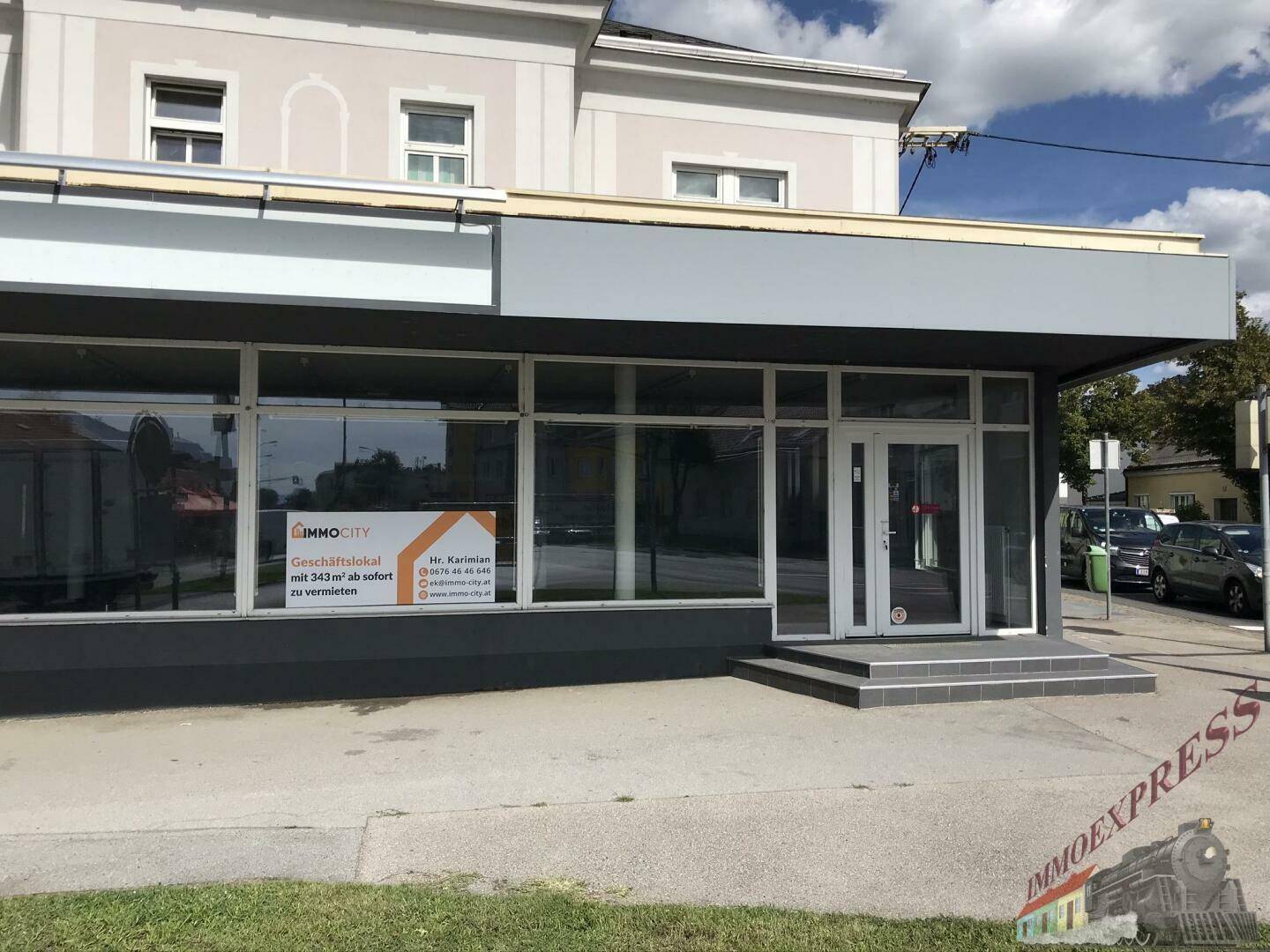 Eingangsbereich des Geschäftslokals mit großen Glastüren und Schaufenstern, direkt an der Straße gelegen.