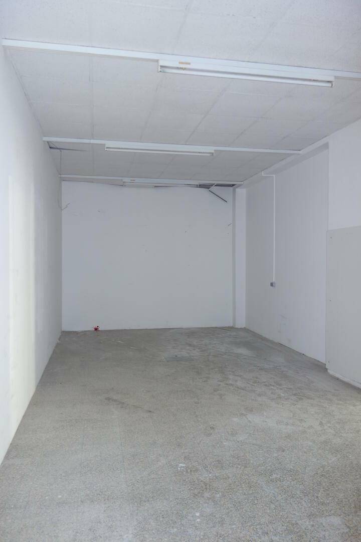 Einfacher Lagerraum mit Betonboden und weißen Wänden, ausgestattet mit Deckenleuchten.