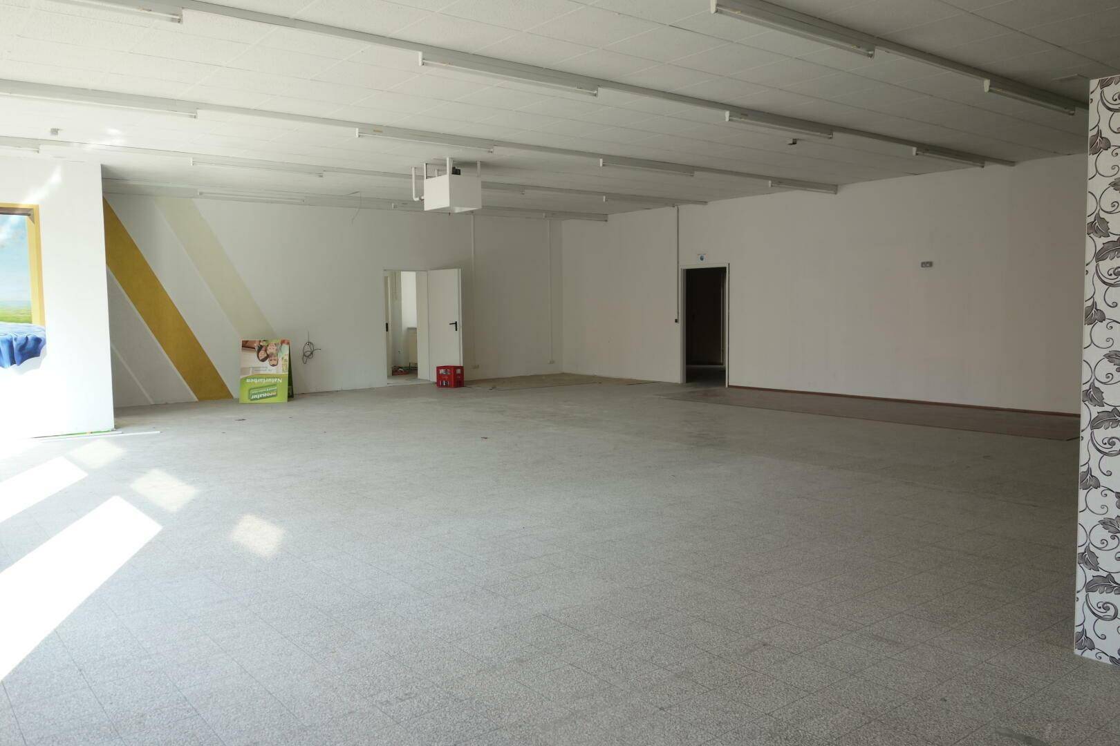 Weitläufiger Gewerberaum mit Fliesenboden und hellen Wänden, der viel Potenzial für verschiedene Geschäftskonzepte bietet.