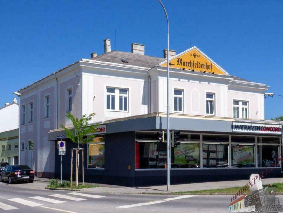Historisches Gebäude an einer Straßenecke mit Geschäftsräumen im Erdgeschoss und Wohnungen darüber.